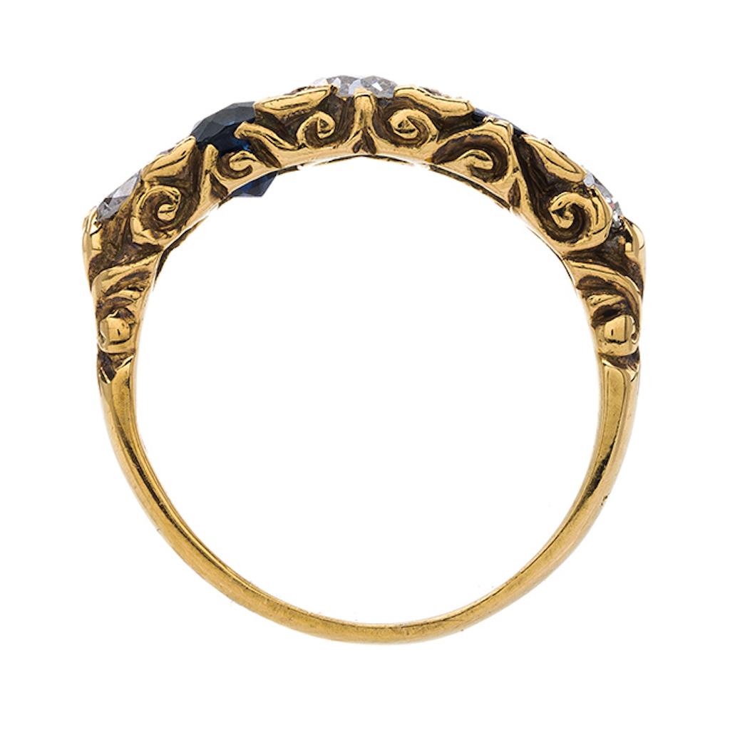 This is a charming and authentic Late Victorian era (circa 1900) 18k yellow gold ring featuring a winning sapphire and diamond combination. The ring centers three Old European Cut diamonds that total approximately 0.55ct in weight and graded H-J