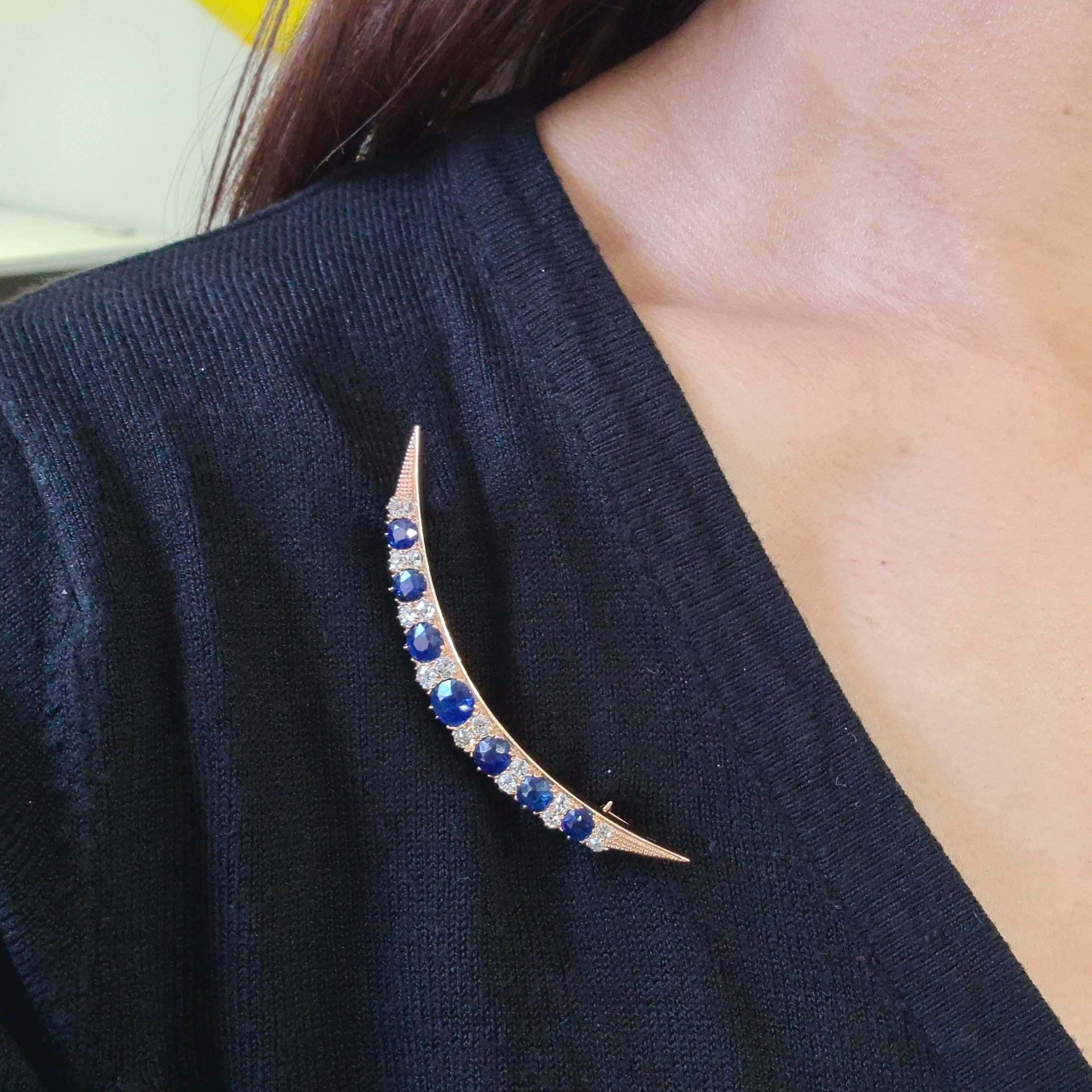 A Victorian sapphire and diamond crescent brooch, set with seven, round faceted sapphires, graduating in size, alternating with eight pairs of old-cut diamonds, in claw and grain settings, the ends of the crescent are embossed, the inner curve is
