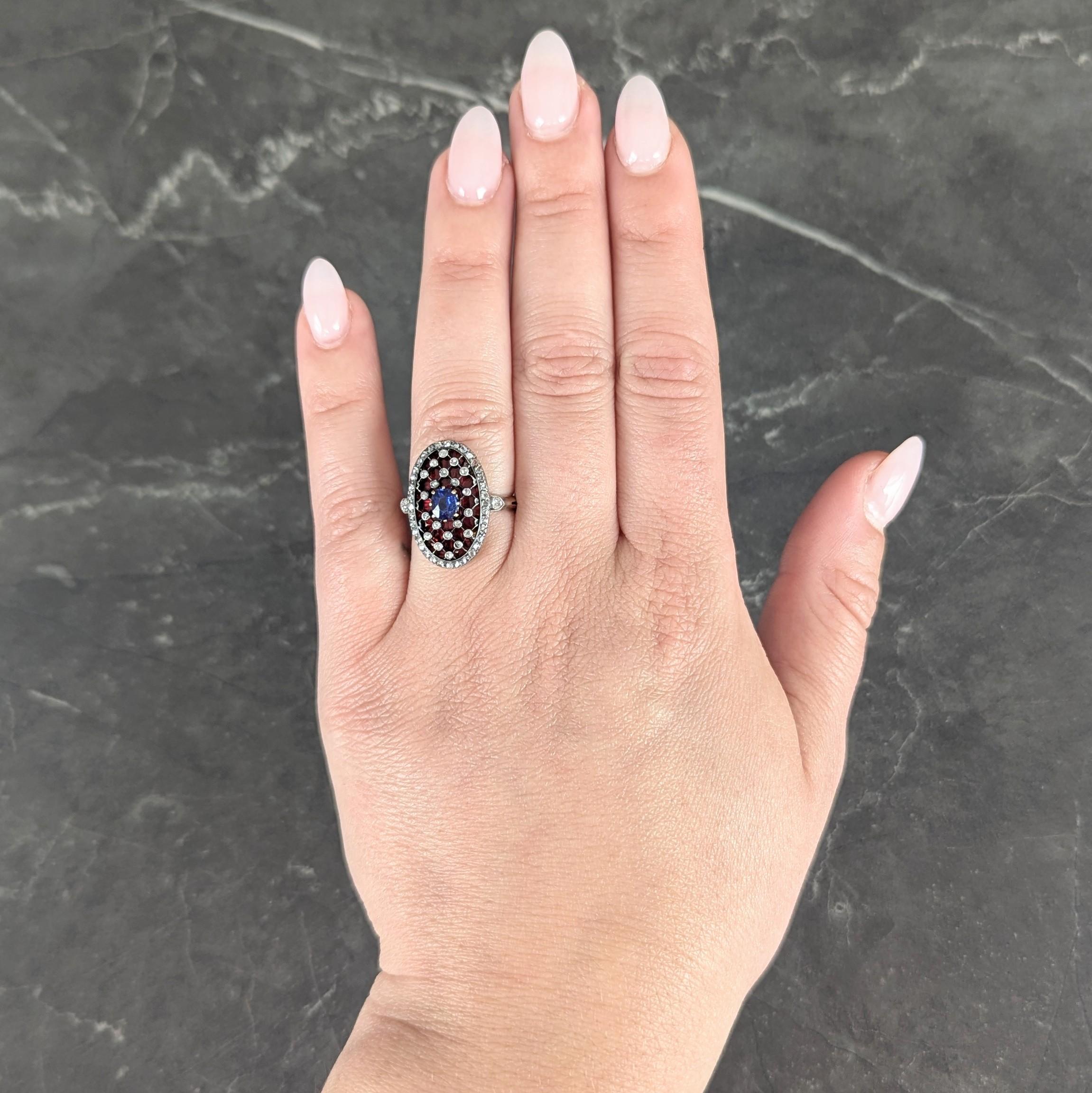 Centering a cushion cut sapphire weighing approximately 0.55 carat - transparent medium blue
Prong set in yellow gold with an elongated silver-topped oval shaped surround
Featuring bezel set rose cut diamonds arranged as lattice motif
Weighing