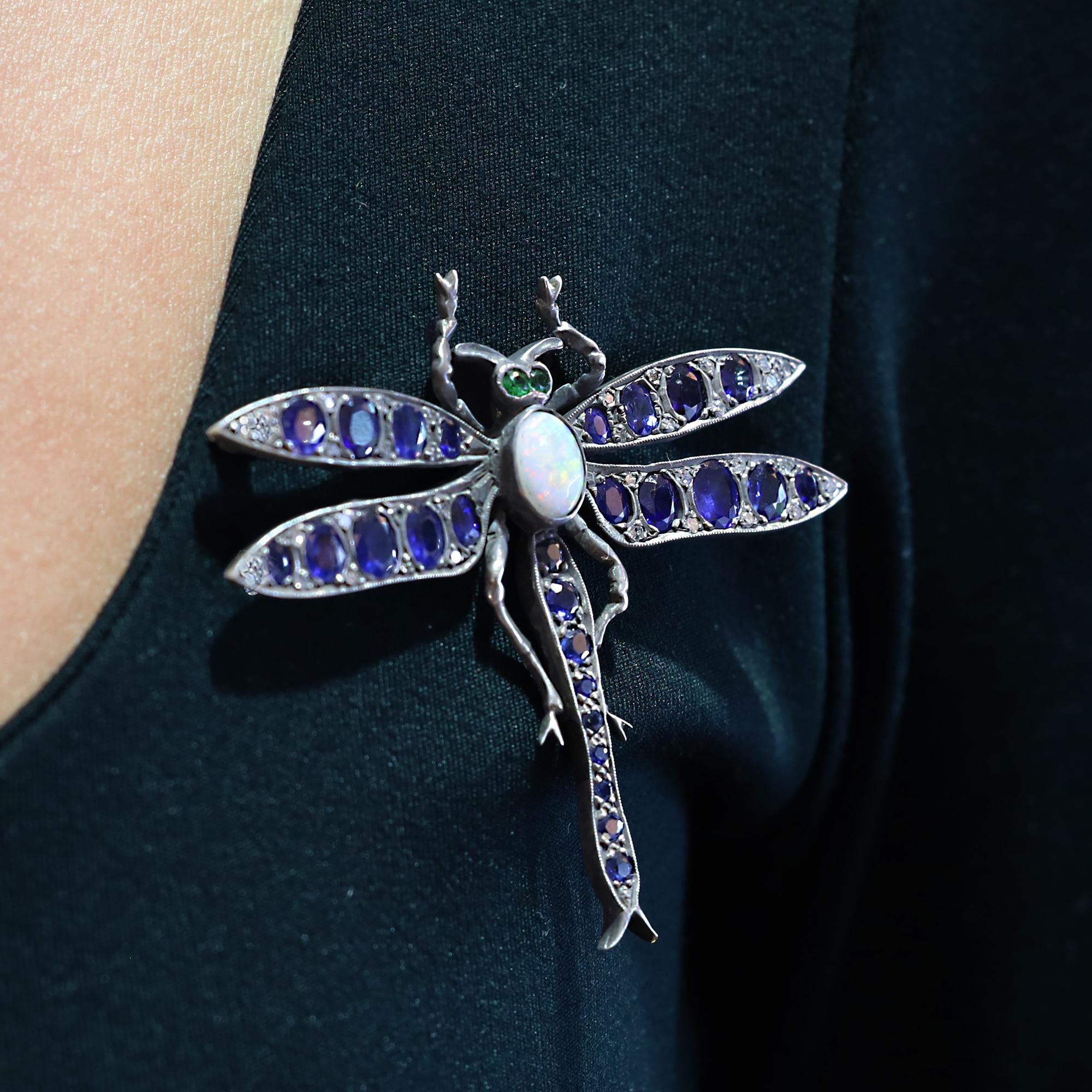 A vivacious and vibrant Victorian dragonfly brooch bursting with character and charm. Crafted 140 years ago of period-correct 14 karat gold and silver, the wings and body adorned with numerous, velvety blue and bright sapphires, diamonds, tsavorite