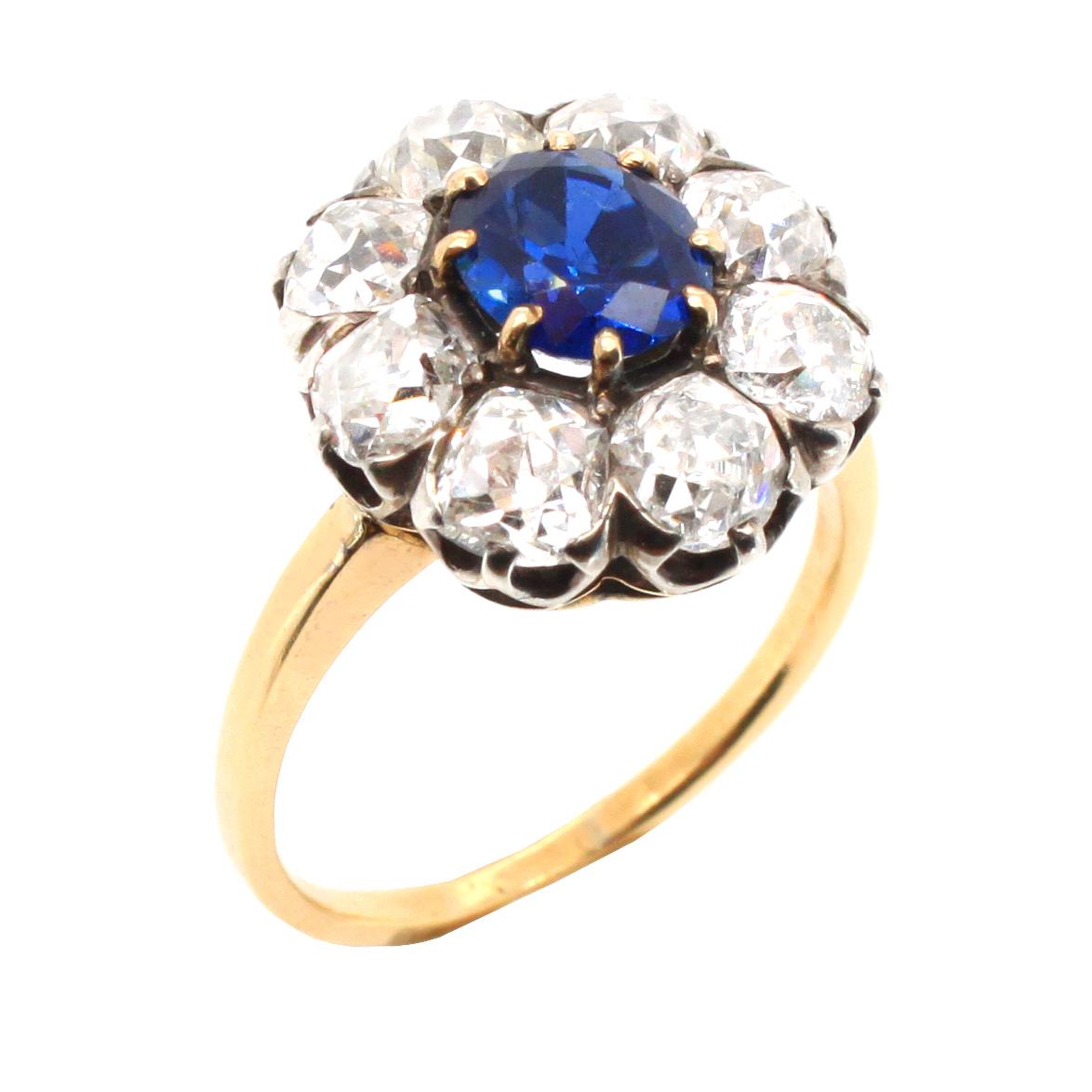 An antique Victorian sapphire and diamond cluster ring, ca. 1880s. The central cushion shaped sapphire weighs circa 1.5 carats and is a natural, not heat treated, gemstone -  accompanied by a gemological certificate. It is surround by a diamond