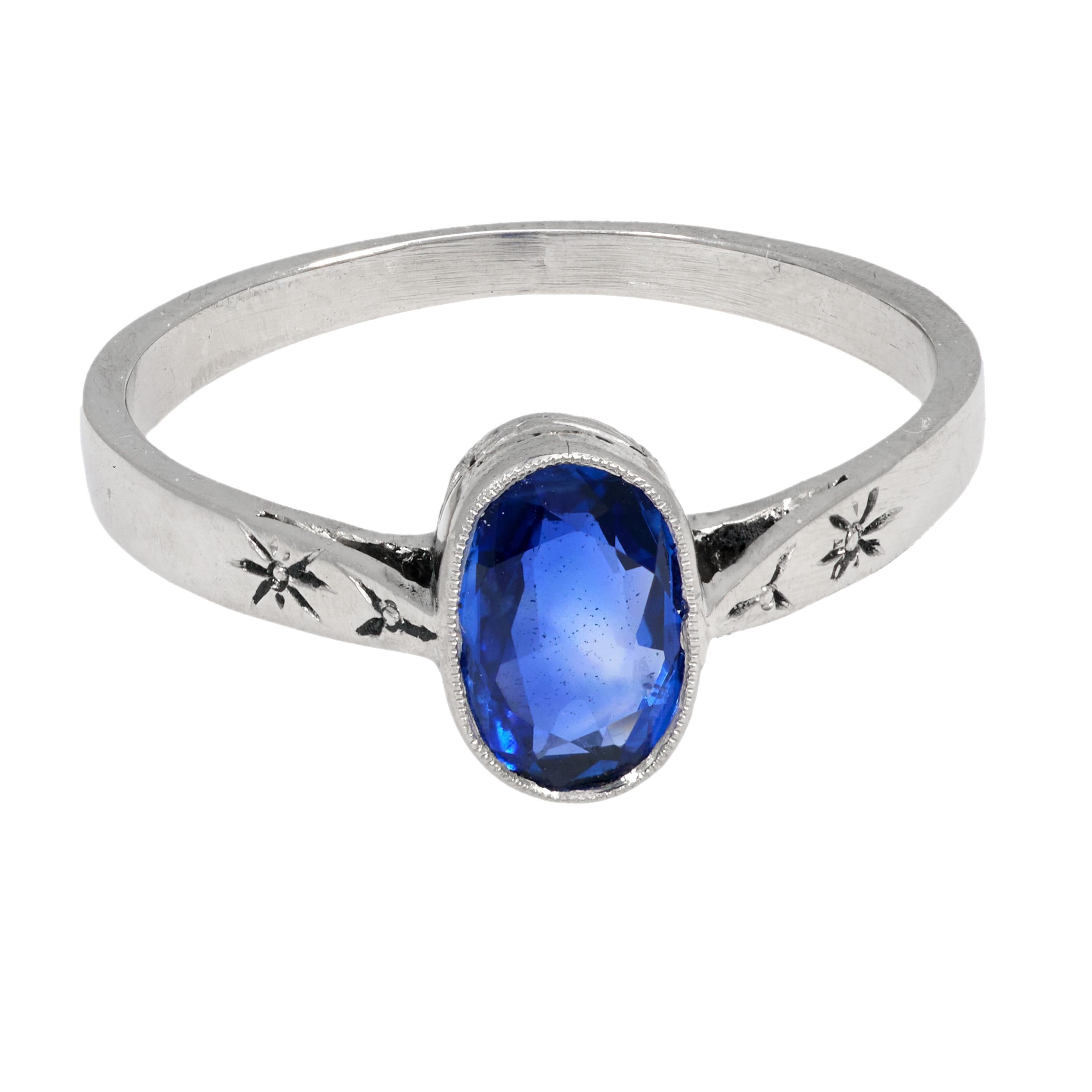 This Victorian platinum ring centers an approximately .70 carat oval cut blue sapphire in a sleek bezel setting, showcasing refined simplicity and antique elegance. Crafted around the 1900s with a maker’s hallmark, the piece blends rich color with