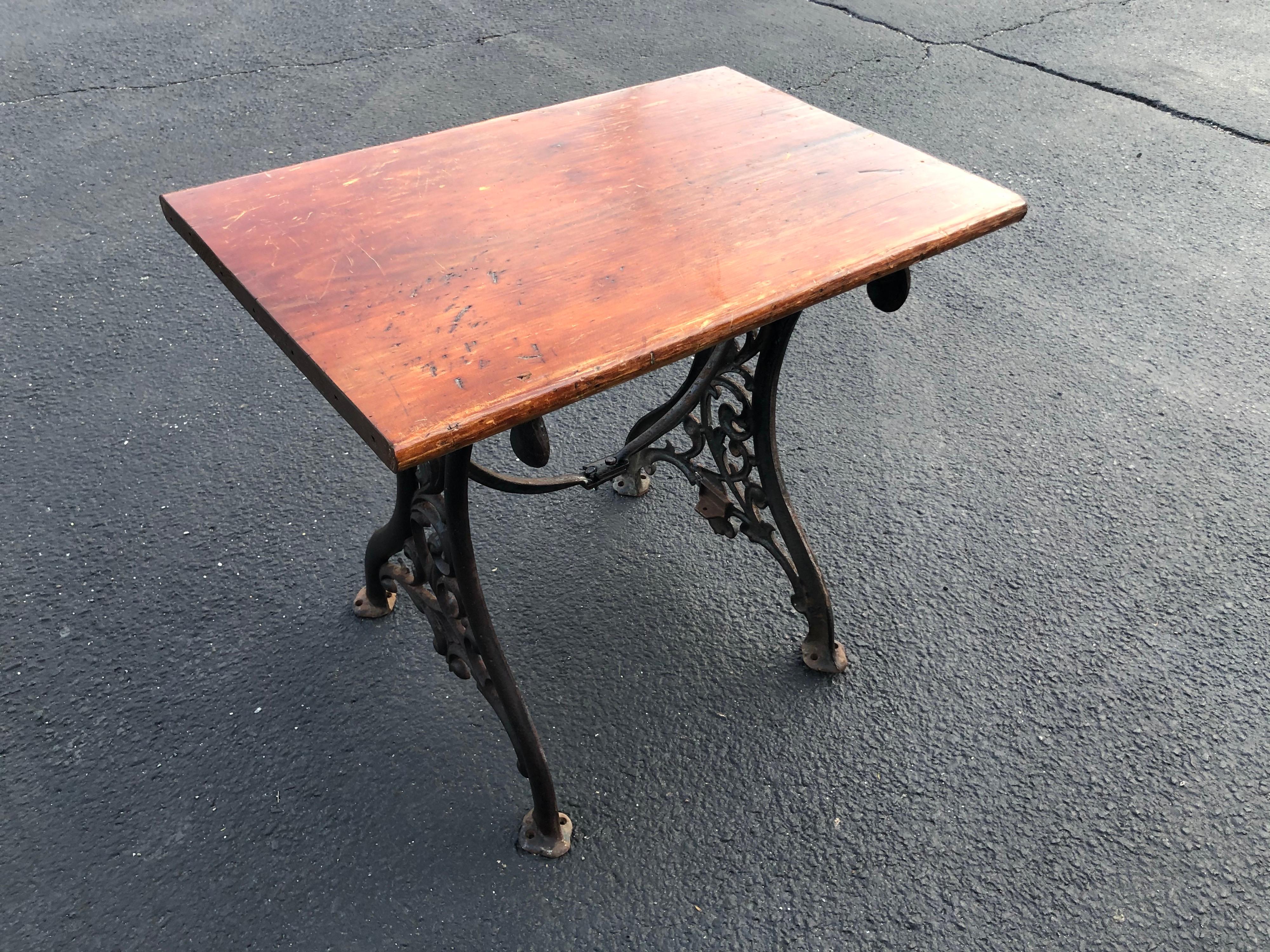 Victorian school desk or sewing table. Classic embellished iron sides make up this beauty. With a rustic distressed pinewood top and holes in the iron feet to be bolted into the ground. Typical for early school classroom desks or for sewing