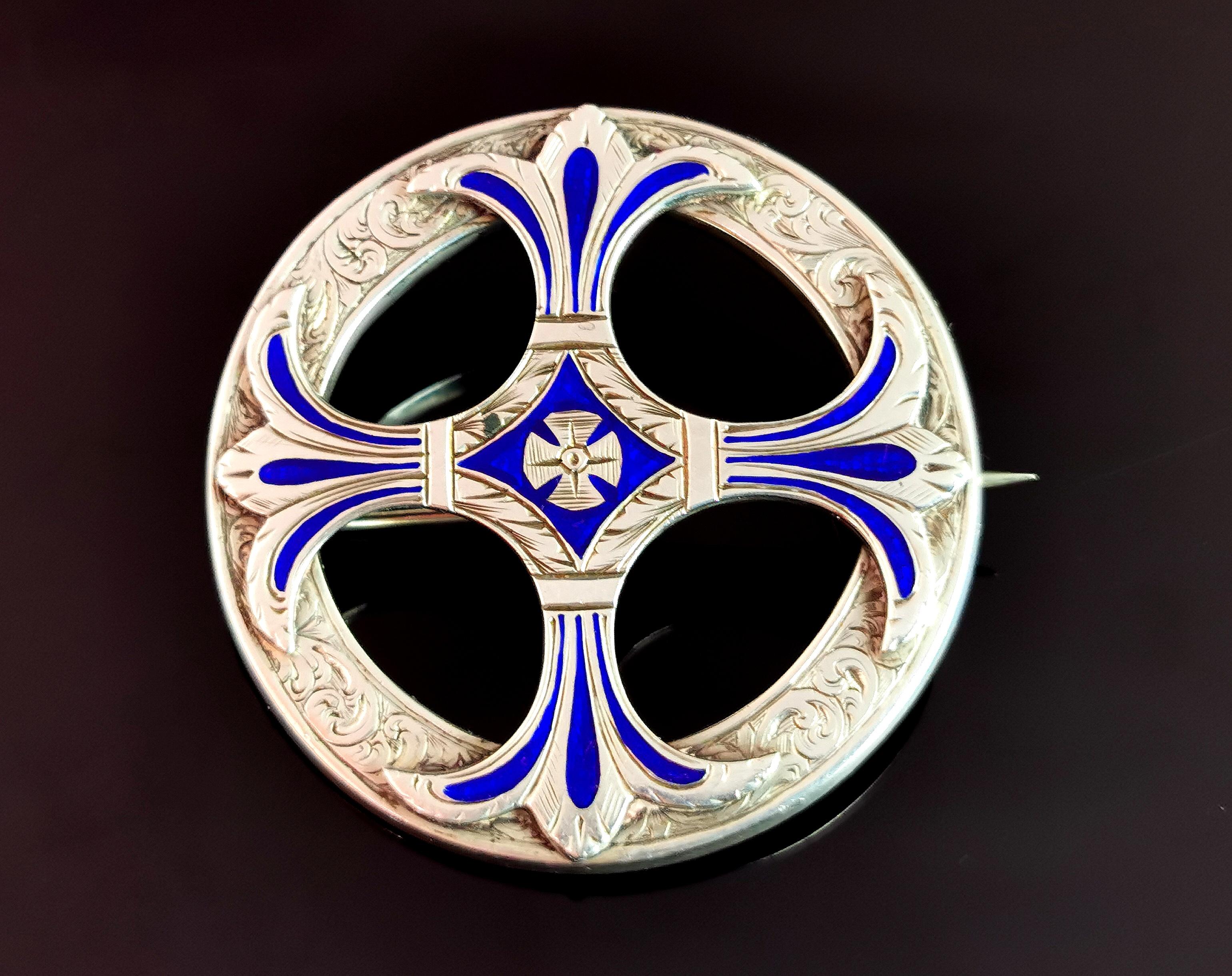 A beautiful and highly detailed antique Scottish sterling silver and cobalt blue enamel brooch or kilt pin.

It is a large sized brooch, circular in shape with a mounted celtic Cross to the centre.

It is heavily engraved all over and has a tudor