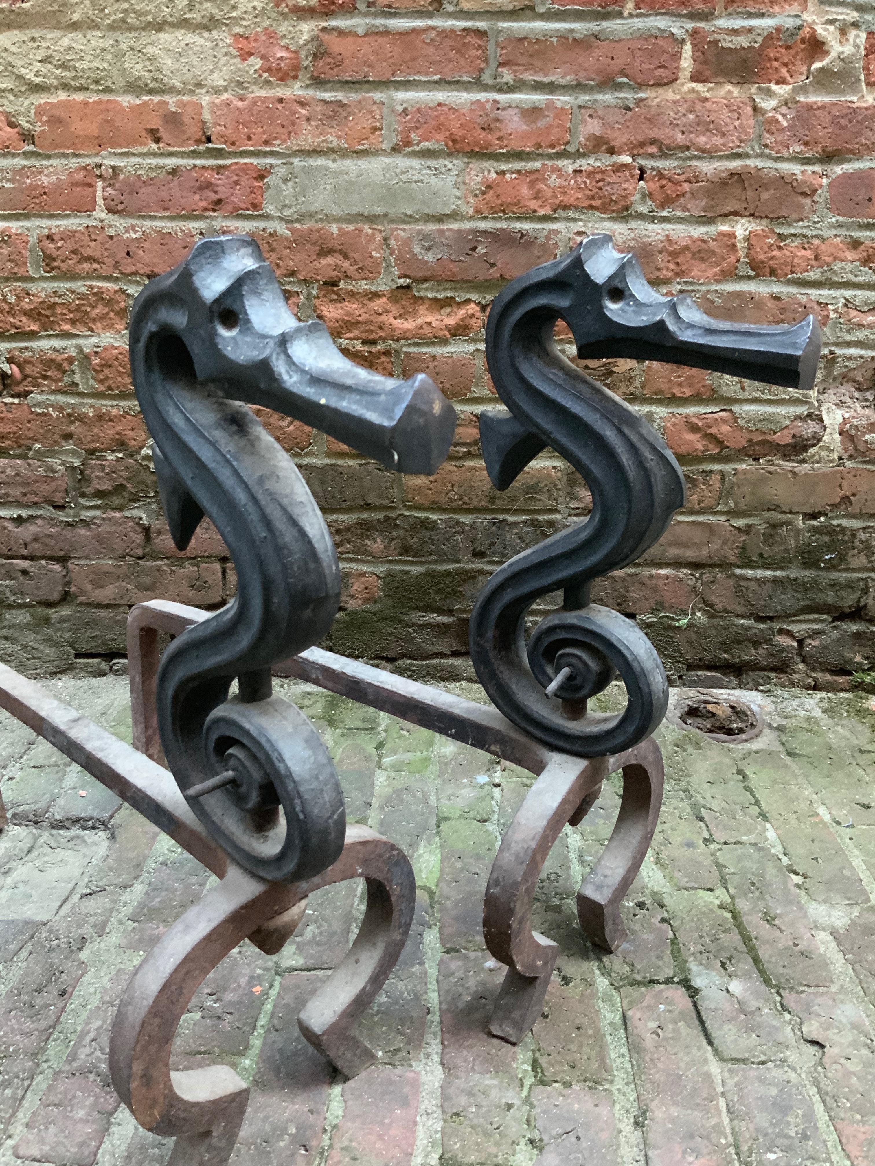 Sublime pair of heavy duty andirons. Stylized late Victorian seahorse andirons. Very good condition considering their age and use. Wear, rusting and pitting to the stands. Structurally sound and sturdy.

Measures: 28