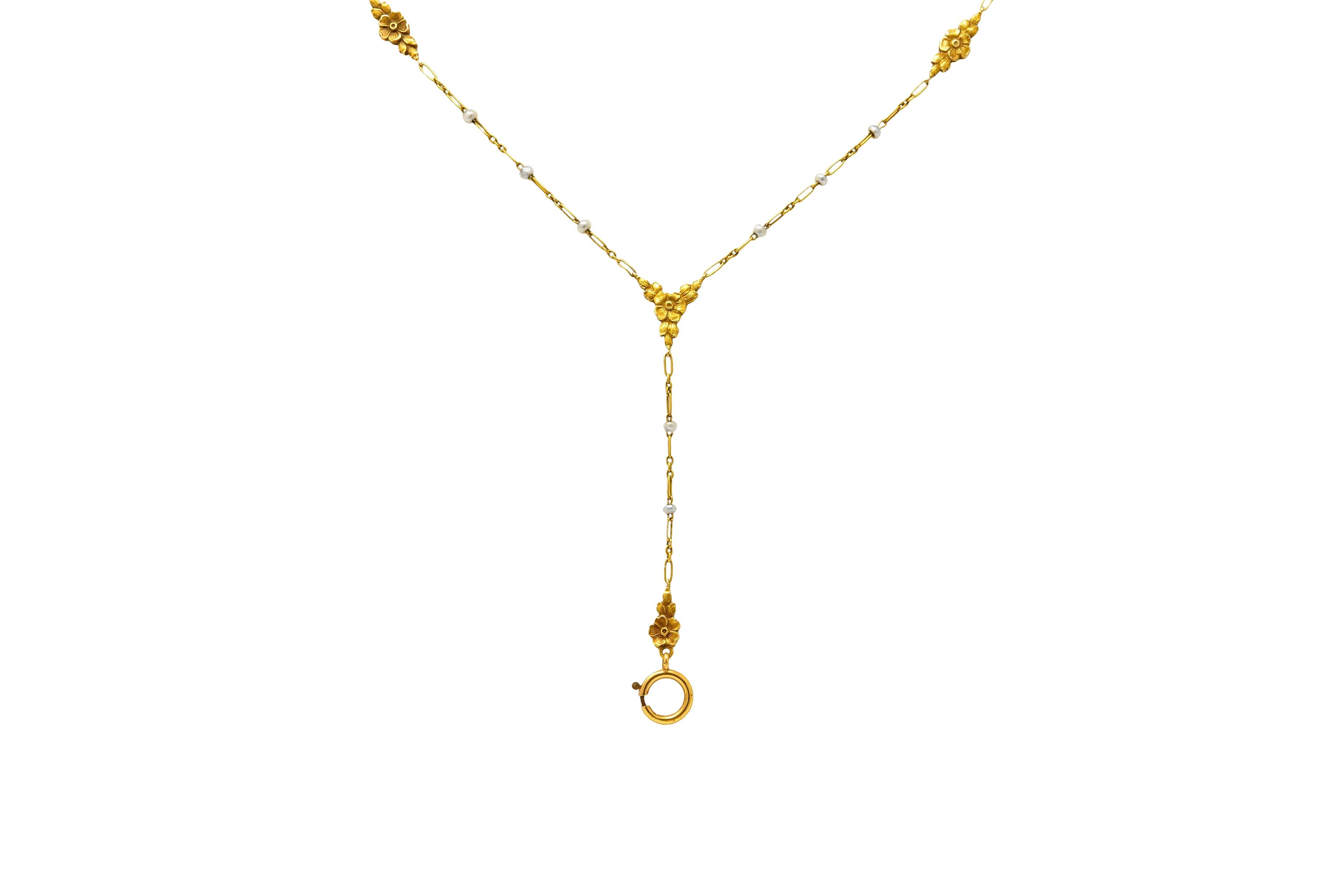 Lariat style necklace comprised of elongated links with seed pearl accents measuring approximately 2.0 mm, gray in body color and very well matched

With floral stations flanked by leaves throughout, matte gold with engraved lines for