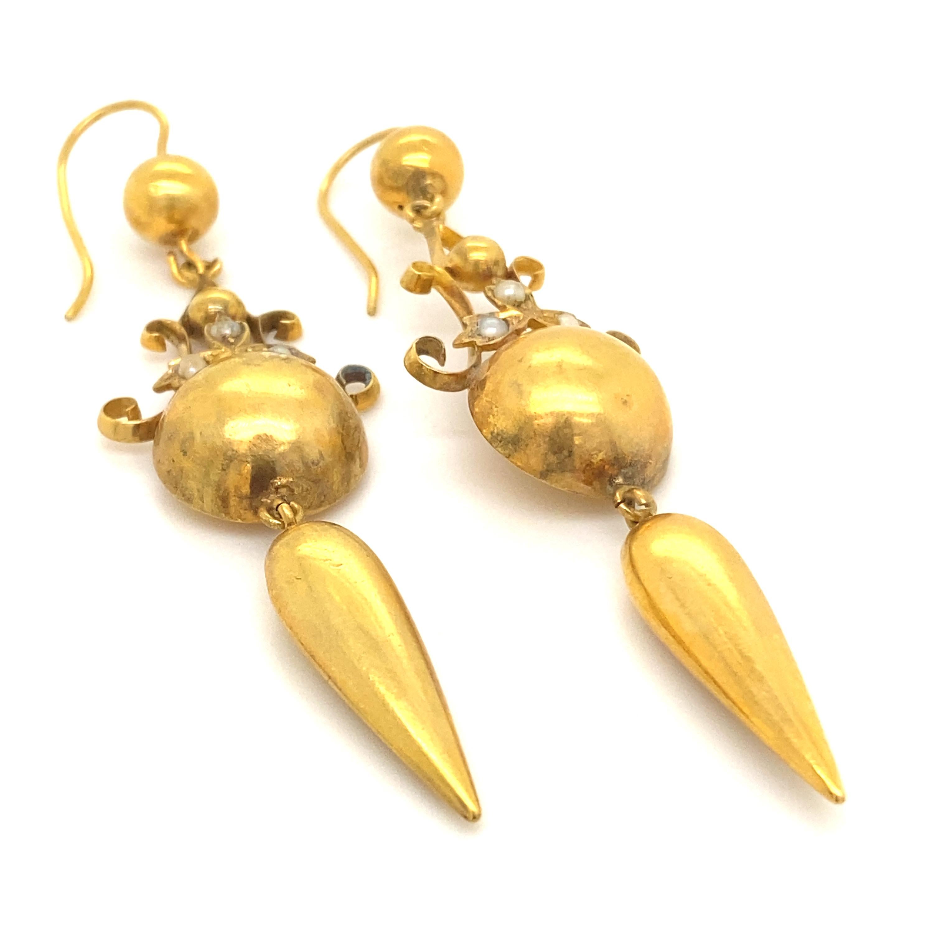 A pair of Victorian seed pearl 18 karat yellow gold drop earrings.

Featuring half balls and tassels suspended from hook and wire fittings, topped with open wirework designs each earring studded with three sweet seed pearls.

These are crafted from