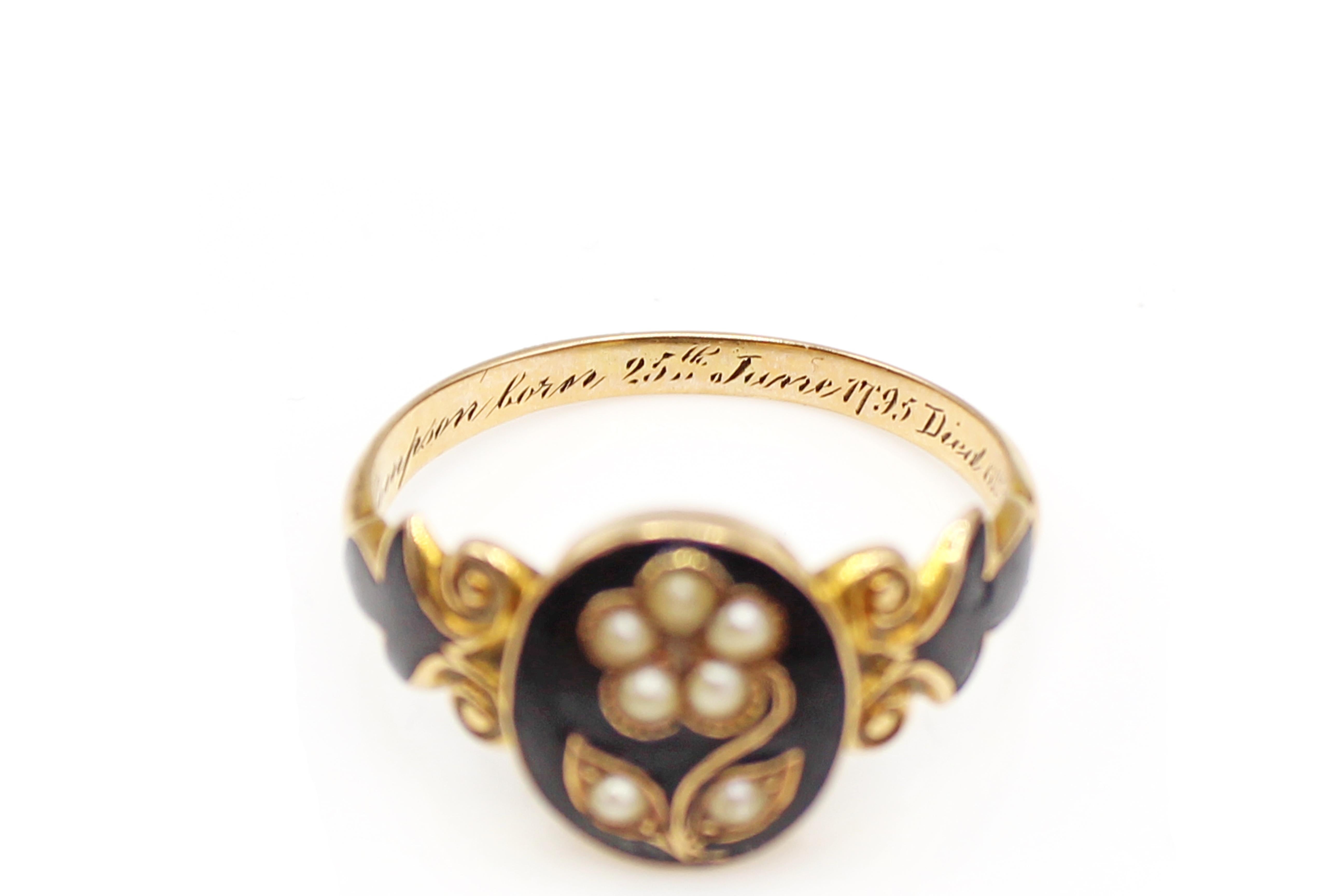 A Victorian mourning ring with a seed-pearl forget-me-not flower on a black-enamel bezel and a locket of hair to the reverse, the inside shank engraved, 'Peter Thompson born 25th June 1795 died 6th May 1865'.The 14 Karat yellow gold band is