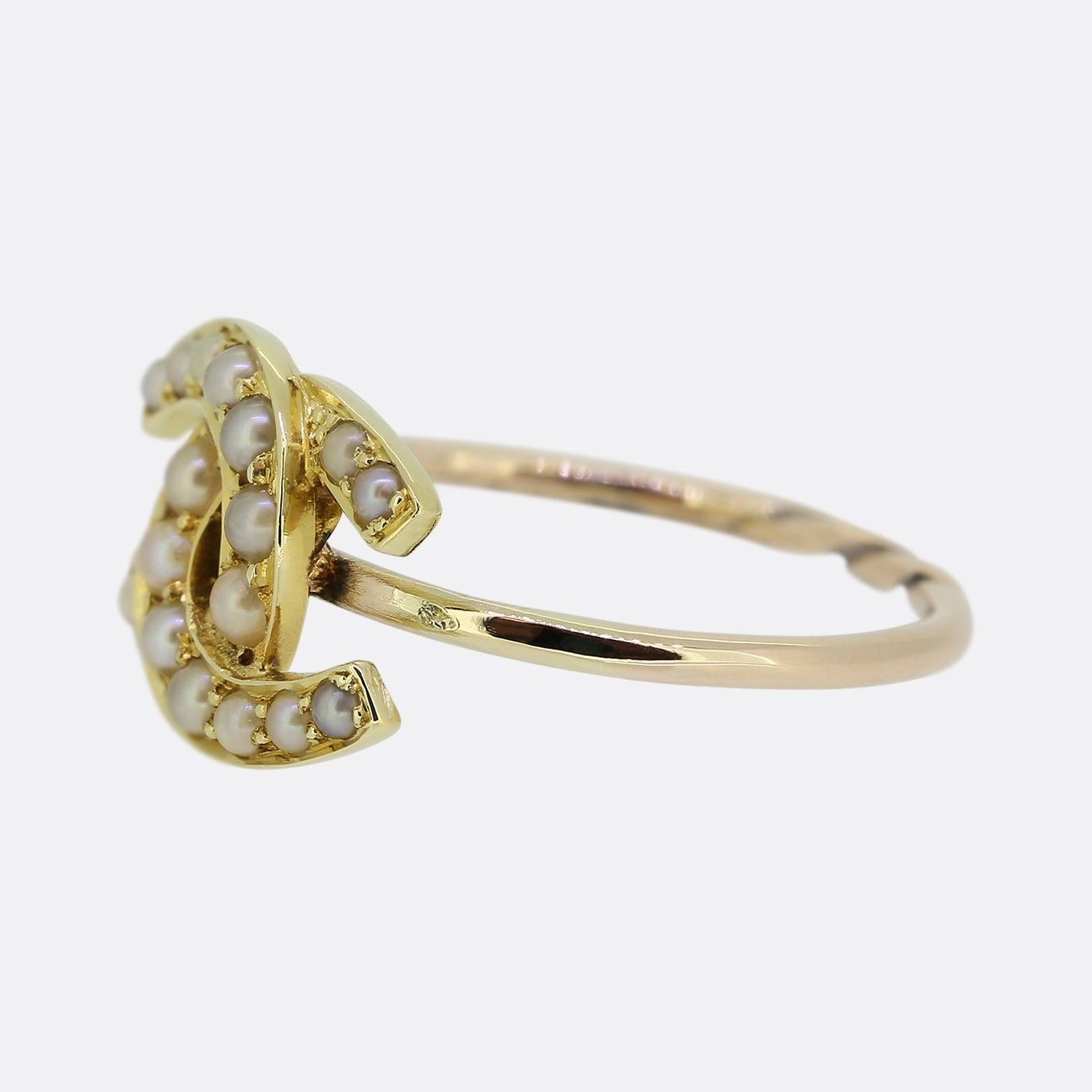Here we have a charming Victorian double horseshoe ring. The face has been crafted into two interlocking horseshoes pervaded with a single row of round seed pearls which sit atop a rose gold band. 

This piece started life as an antique stick pin