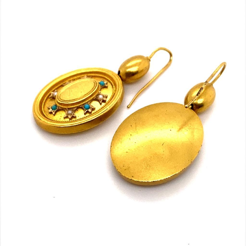 A pair of Victorian seed pearl and turquoise 18 karat yellow gold drop earrings.

Featuring bold oval discs suspended from hook and wire fittings, set to their base with cushion shaped baubles of 18 karat yellow gold.

Each chunky oval is set to its