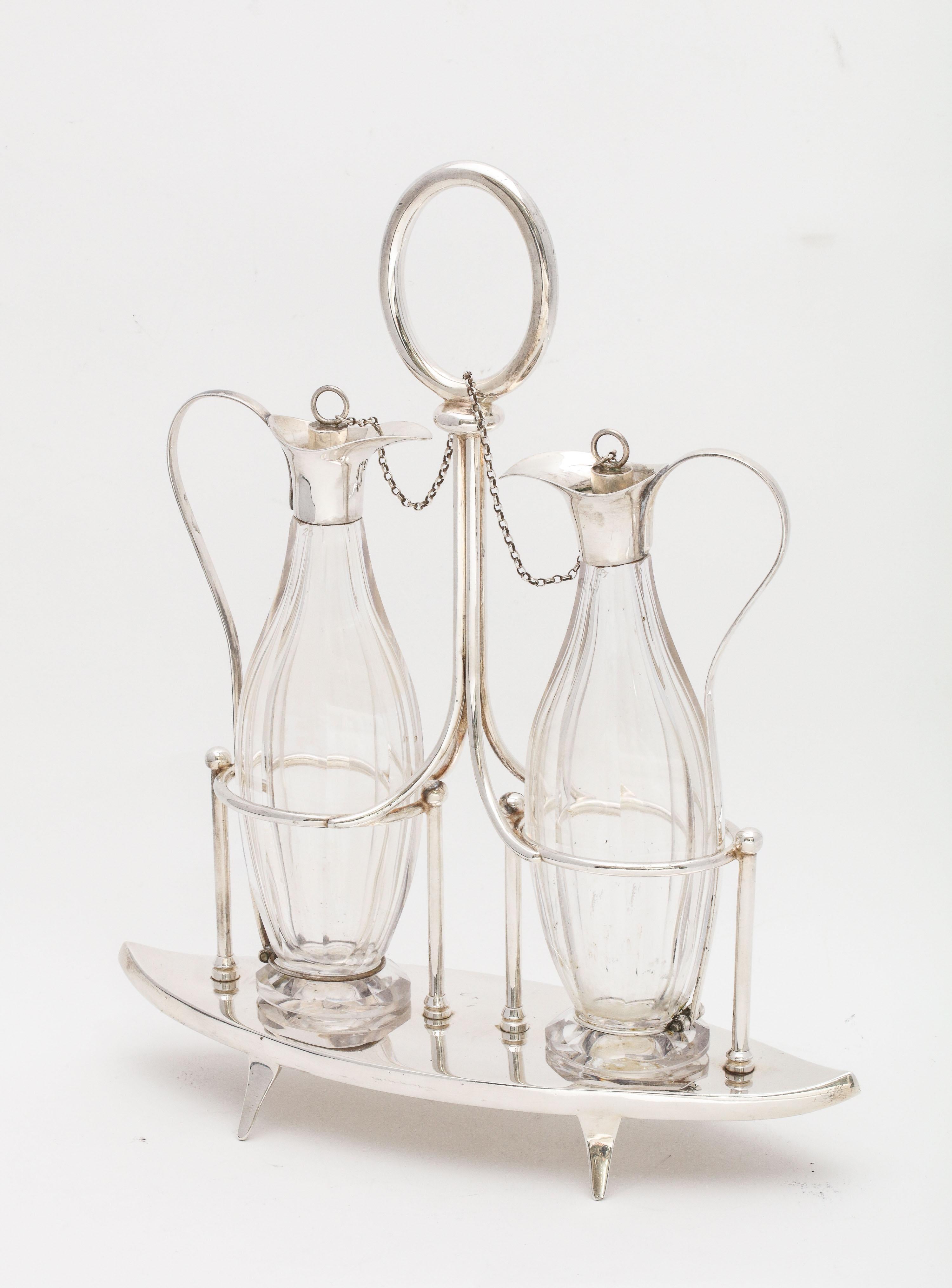 Victorian, Sheffield plated, footed, two bottle cruet set (consisting of the two bottles, stoppers and stand), Sheffield, England, circa 1878, William Hutton and Sons - makers. Stand measures: 10 1/8 inches high (to top of handle) x 8 1/2 inches