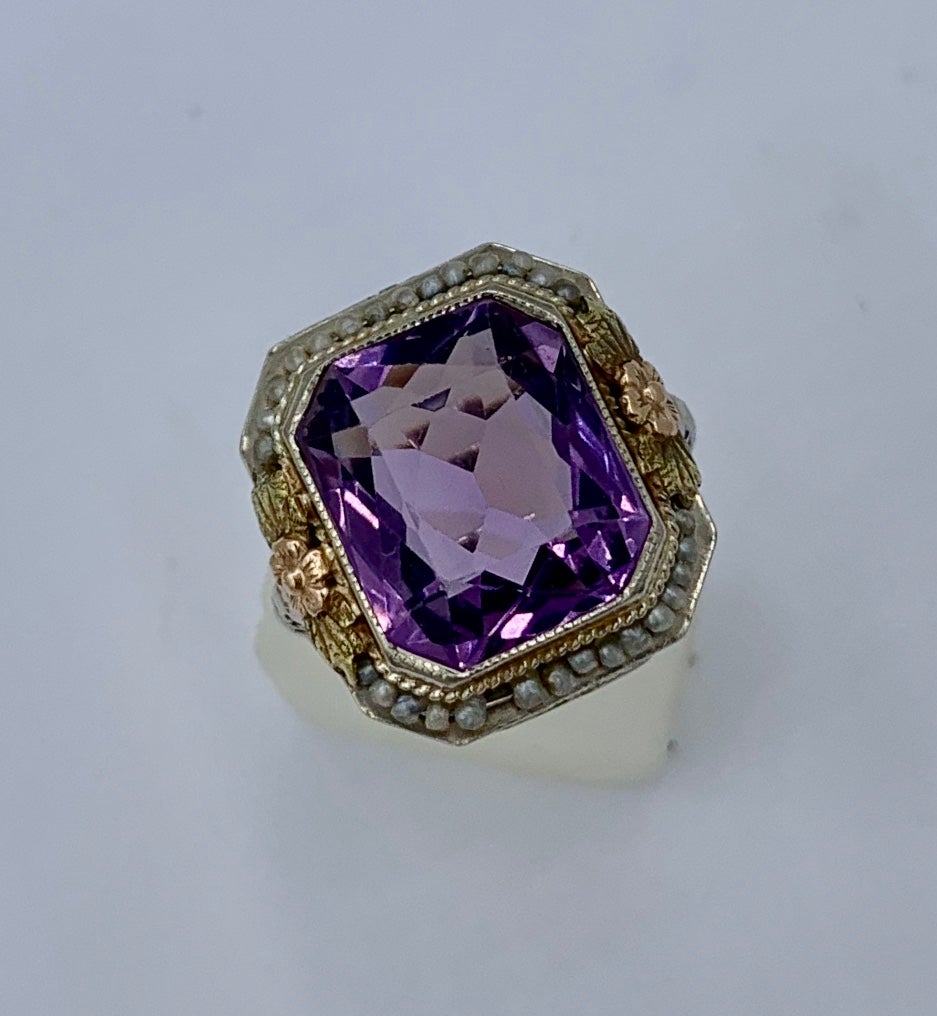 This is an exquisite Antique Victorian Ring with a spectacular Rectangular Cushion Cut Faceted Siberian Amethyst surrounded by a halo of pearls set in a stunning flower motif decorated setting in 14 Karat Yellow and White Gold.  The cushion cut