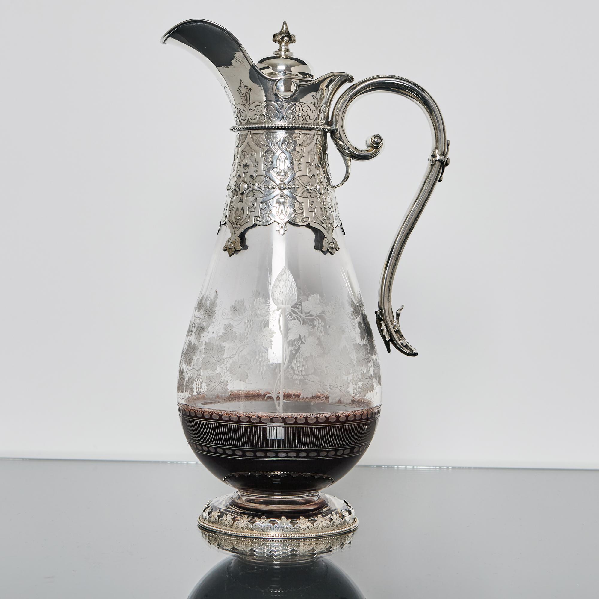 Handsome example of an antique Victorian wine jug. Made by one of the best silversmiths of the era, this piece incorporates fine glass engraving and excellent hand-chased decorations on the silver mounts. 

The teardrop-shaped, hand-blown glass