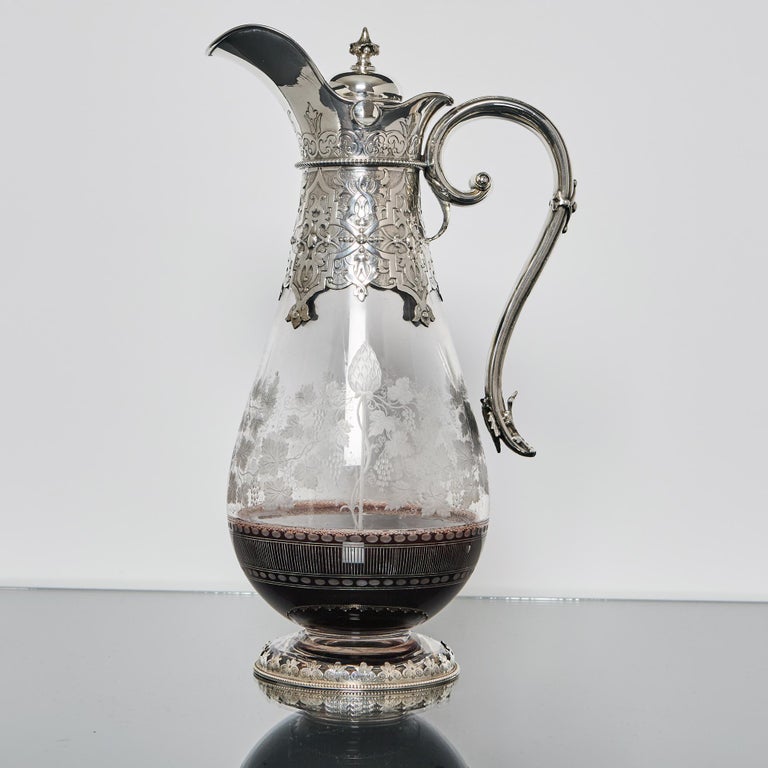 Handsome example of an antique Victorian wine jug. Made by one of the best silversmiths of the era, this piece incorporates fine glass engraving and excellent hand-chased decorations on the silver mounts. 

The teardrop-shaped, hand-blown glass