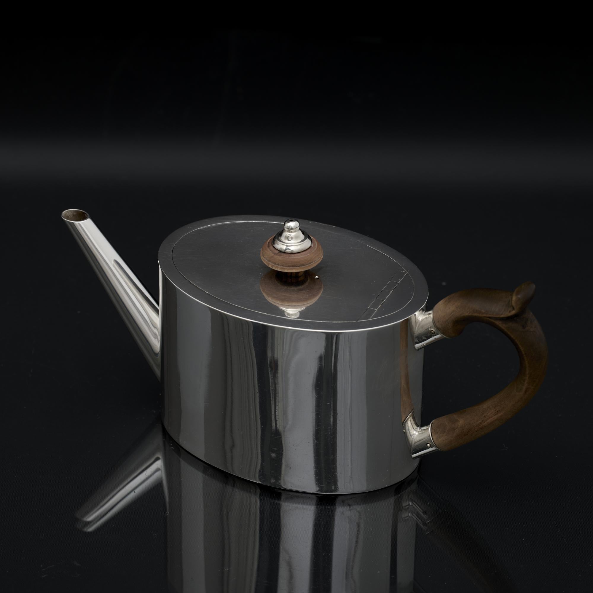 Elegant hand-raised Victorian silver teapot, designed in an 18th century Georgian style with simple and elegant oval body and flat top. The lid is fitted to the pot with a flush jeweller's hinge, an additional mark of quality. The fruitwood handle