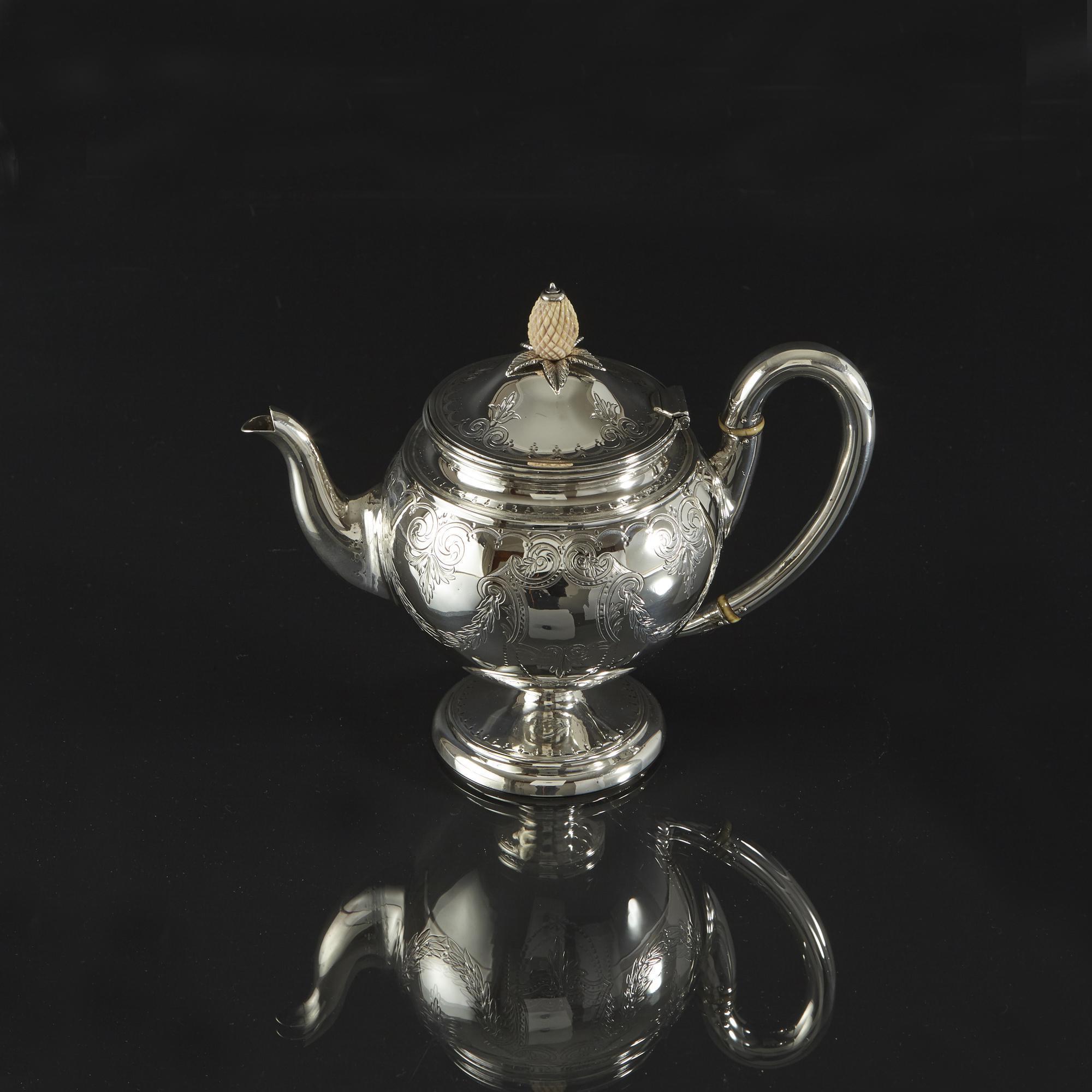This is a pretty bachelor or breakfast teapot with fine crisp hand-engraved decoration of scrolls, leaves and garlands. The round body is mounted on a circular spreading foot and has a slightly domes hinged lid with matching engraving. It has a