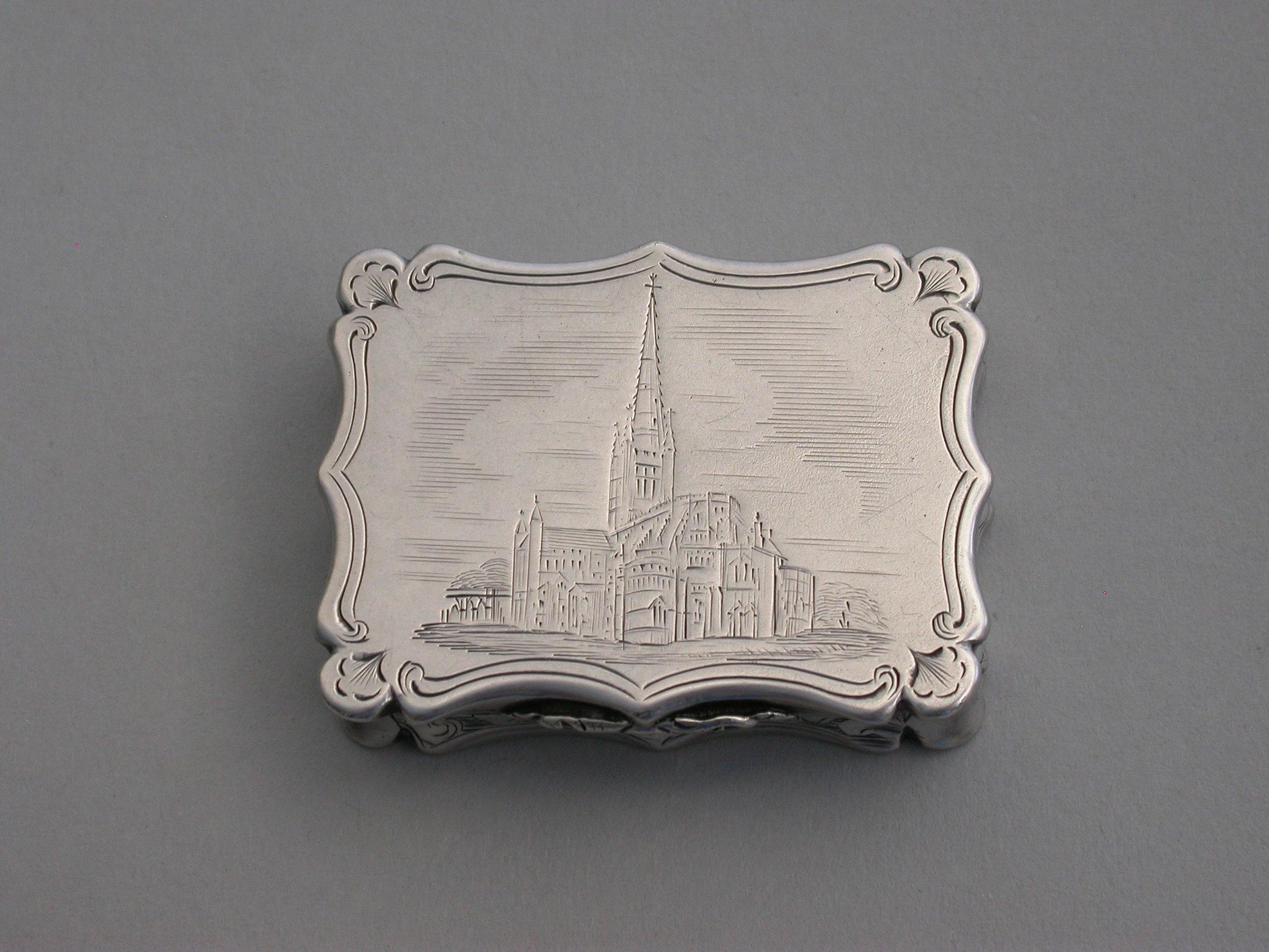 An extremely rare Victorian silver castle-top Vinaigrette of shaped rectangular form, the lid engraved with a scene depicting Norwich Cathedral, the silver gilt interior with intricately pierced foliate scroll grille. The base with scrolled