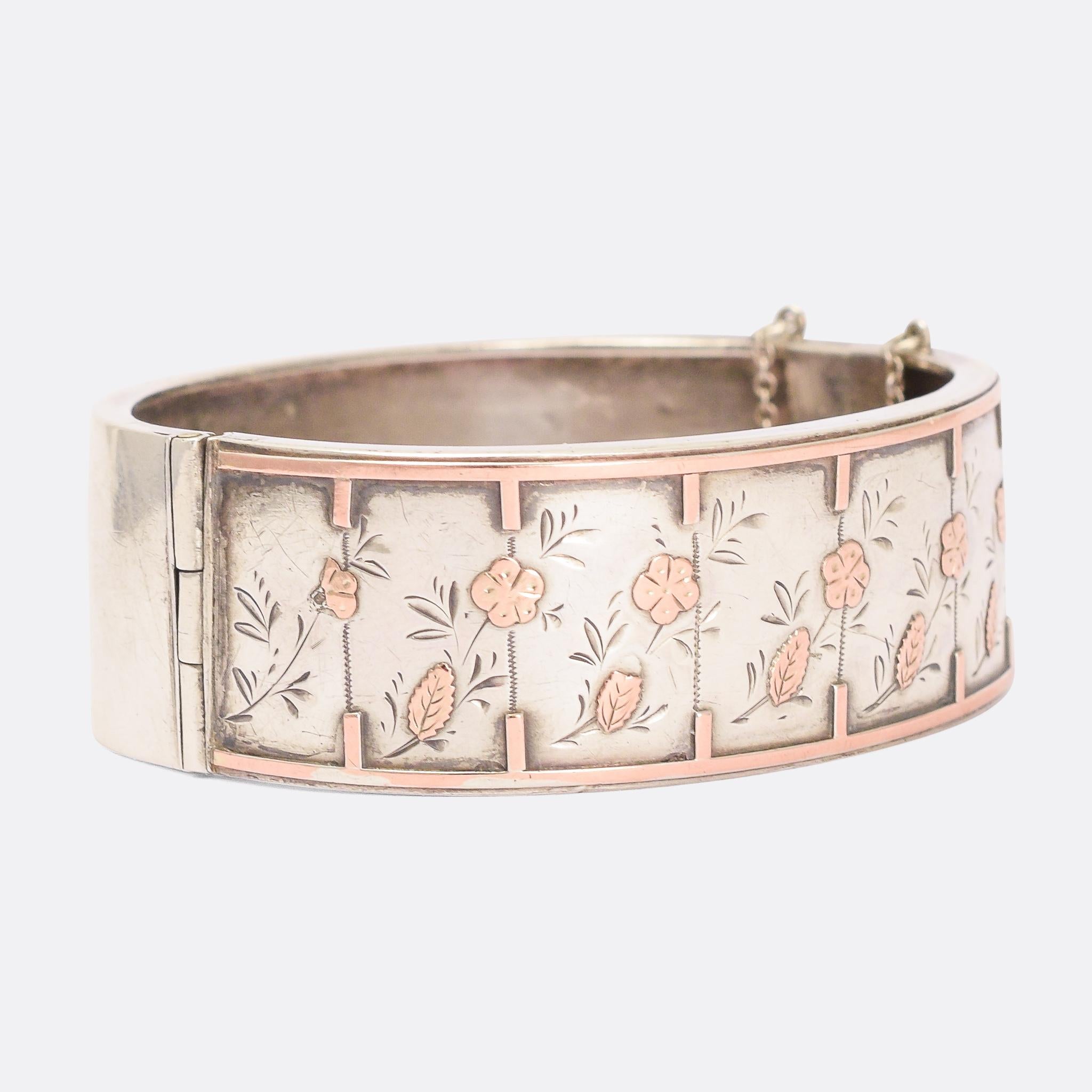 A particularly lovely antique silver cuff bangle. It features applied rose gold flowers and border with chased embellishment, and dates from the latter half of the 19th Century. It has a minimalist look reminiscent of the Aesthetic movement without