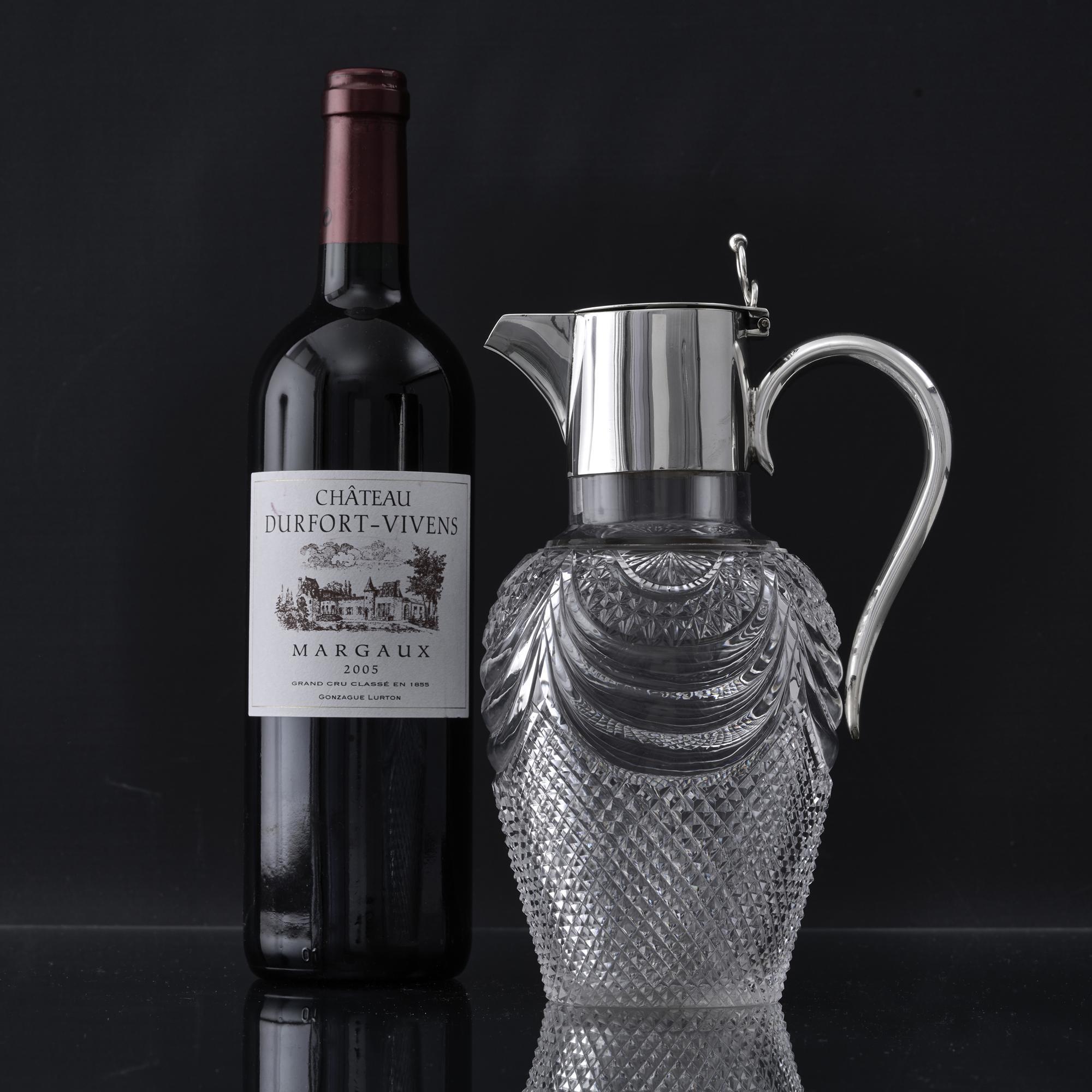 Inverted pear-shaped, antique, cut-glass claret jug with plain sterling silver mounts and an elegant swan-neck silver handle.  The lower part of the crystal body has been finely cut with a faceted pattern, while the upper section includes swag