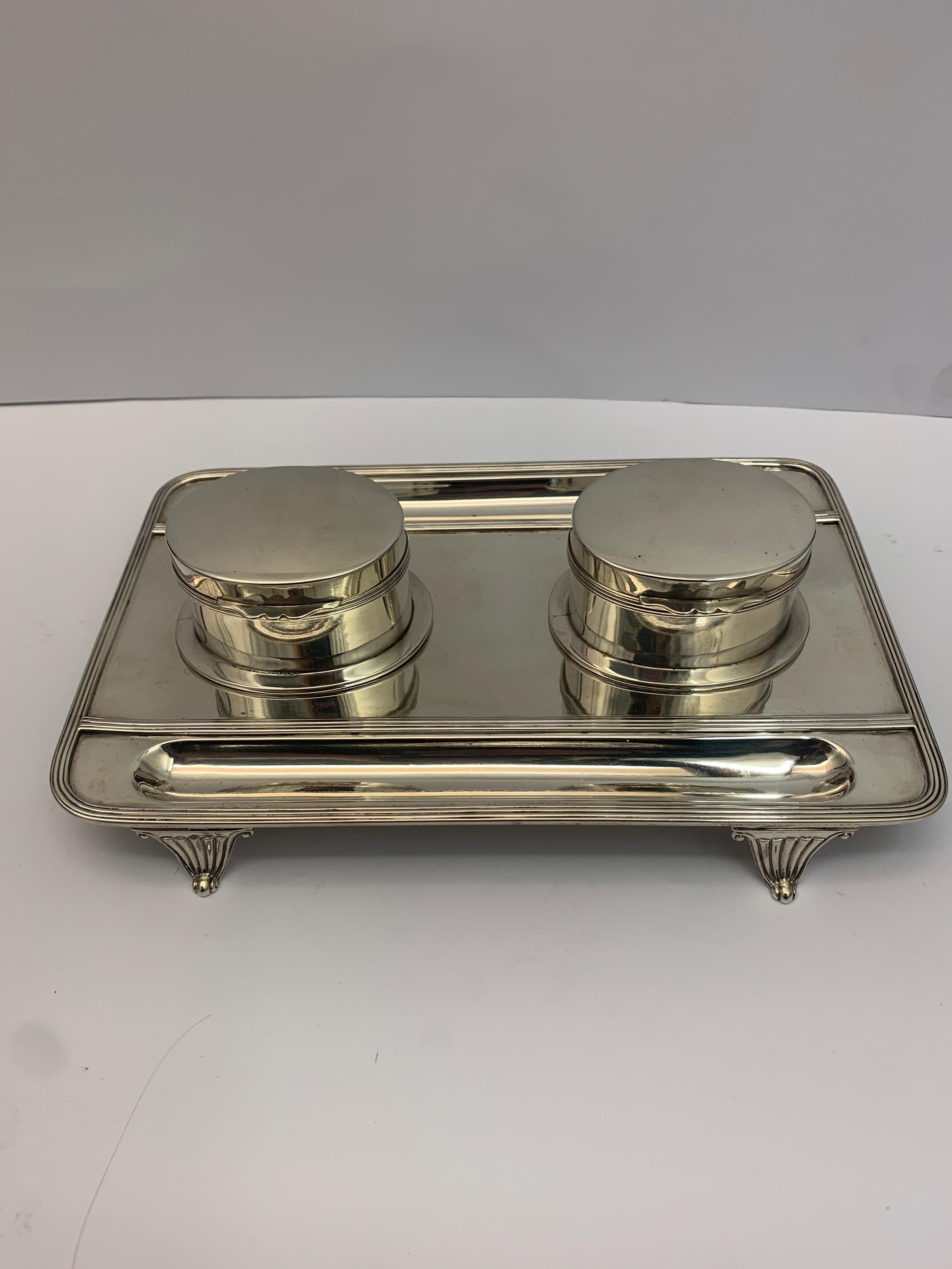 A double silver lidded inkwell on silver tray with 4 small decorative feet. Made in 1892.
