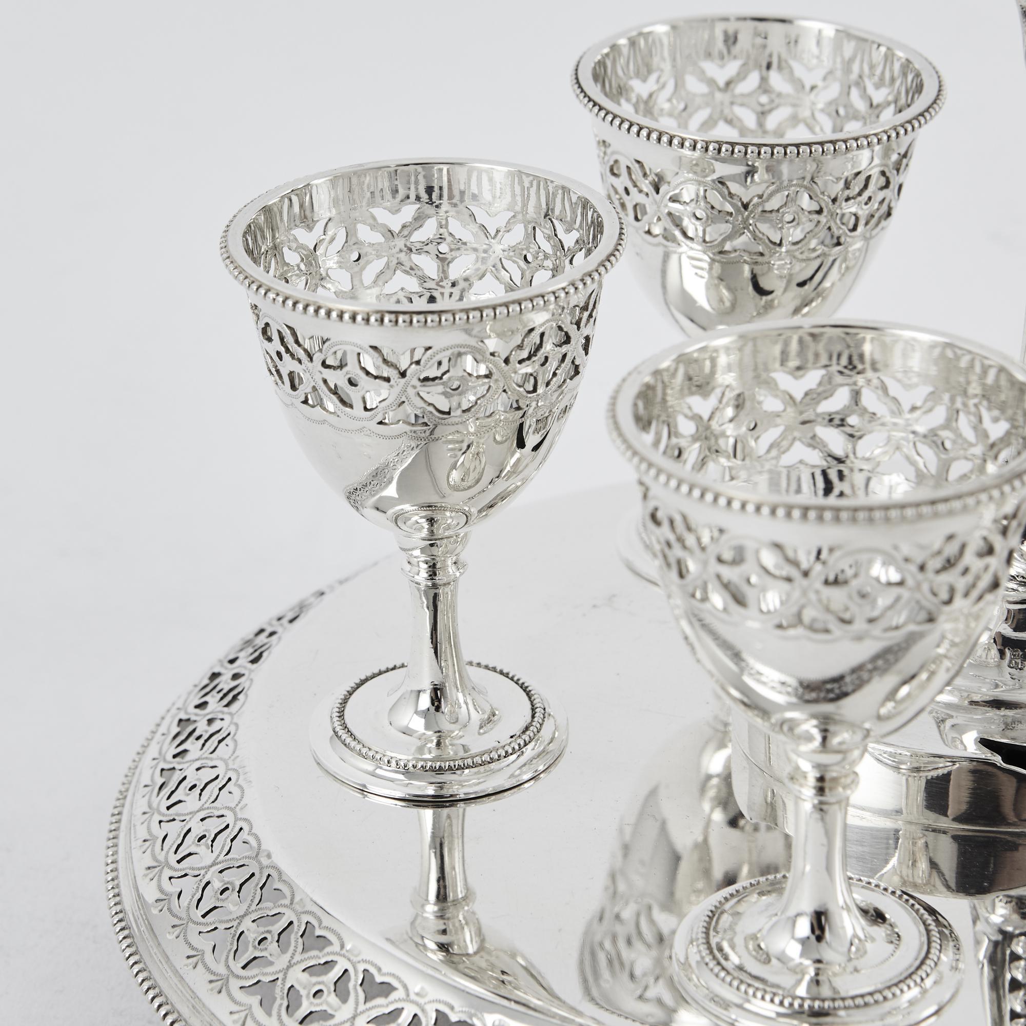 Pretty antique silver cruet frame with six original removable silver egg cups; each held in its place by a silver peg on the base. All pieces are crisply pierced and engraved with delicate bead pattern borders. The frame and each cup are all