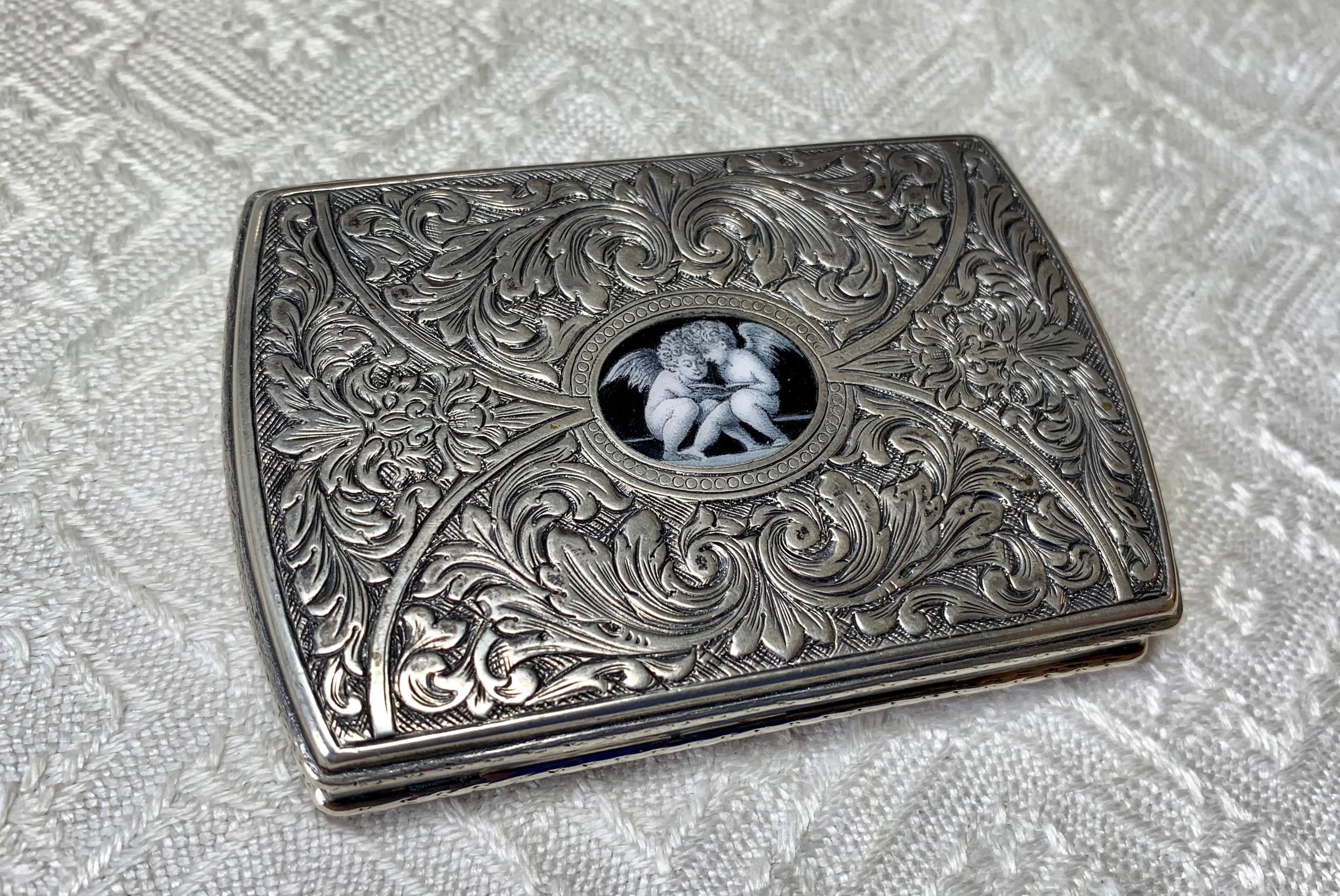 AN EXTREMELY RARE SILVER ENAMEL BOX OF EXTRAORDINARY BEAUTY WITH A CENTRAL GRISAILLE ENAMEL IMAGE OF TWO CHERUB OR ANGELS READING A BOOK - STUNNING QUALITY!  THE SILVER BOX WITH ACANTHUS REPOUSSE AND ENGRAVED WORK WITH FACES ON EITHER SIDE OF THE