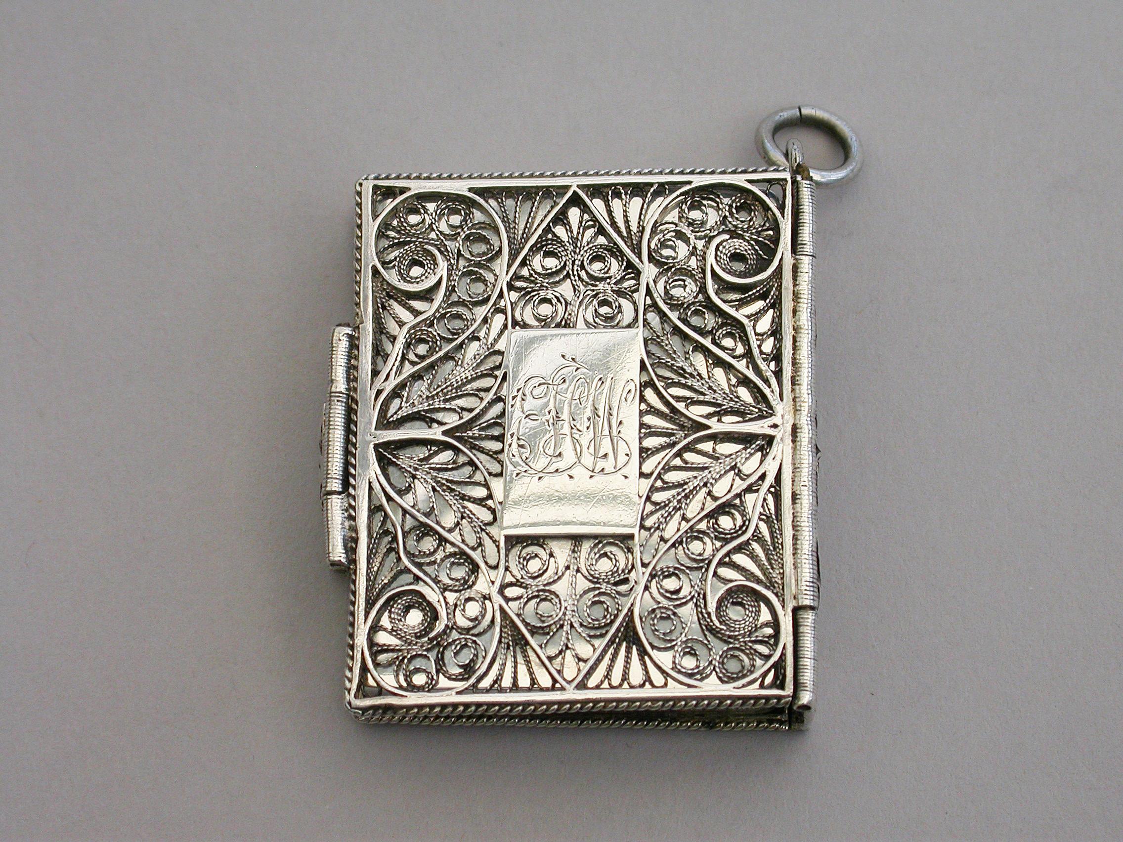 A very rare Victorian silver Vinaigrette made in the form of a family bible with clasp and suspension ring, the Vinaigrette itself with plain surfaces, the outer covers of filigree work with central plaques. The silver gilt grille pierced with