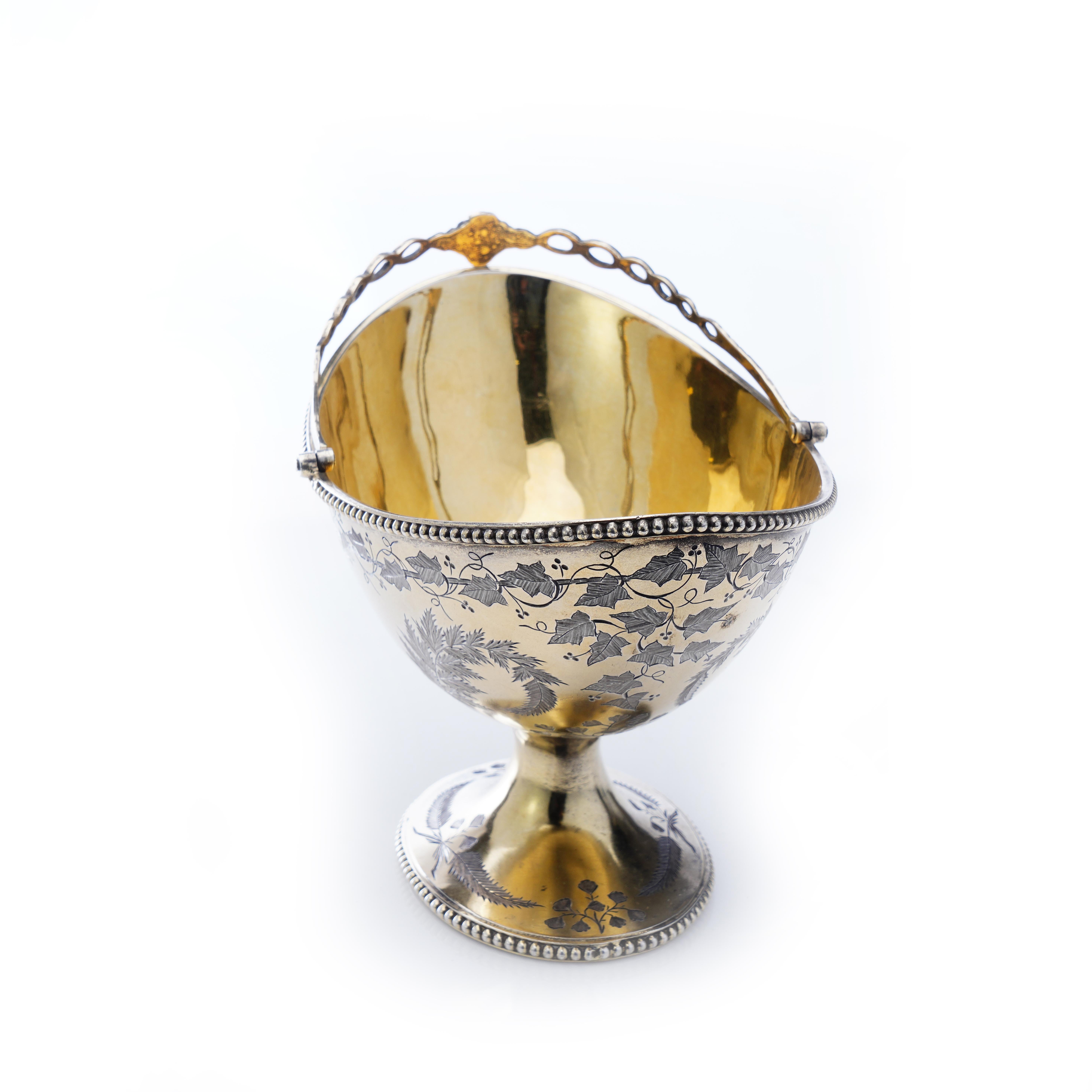 Antique Victorian silver gilt swing handle basket with engraved grape leaves and floral motifs.
Maker: Thomas Smily
Made in England, London, 1873
Fully hallmarked.

Dimensions -
Length x width x height: 16.5 x 11 x 11.5 cm
Weight: 282 grams