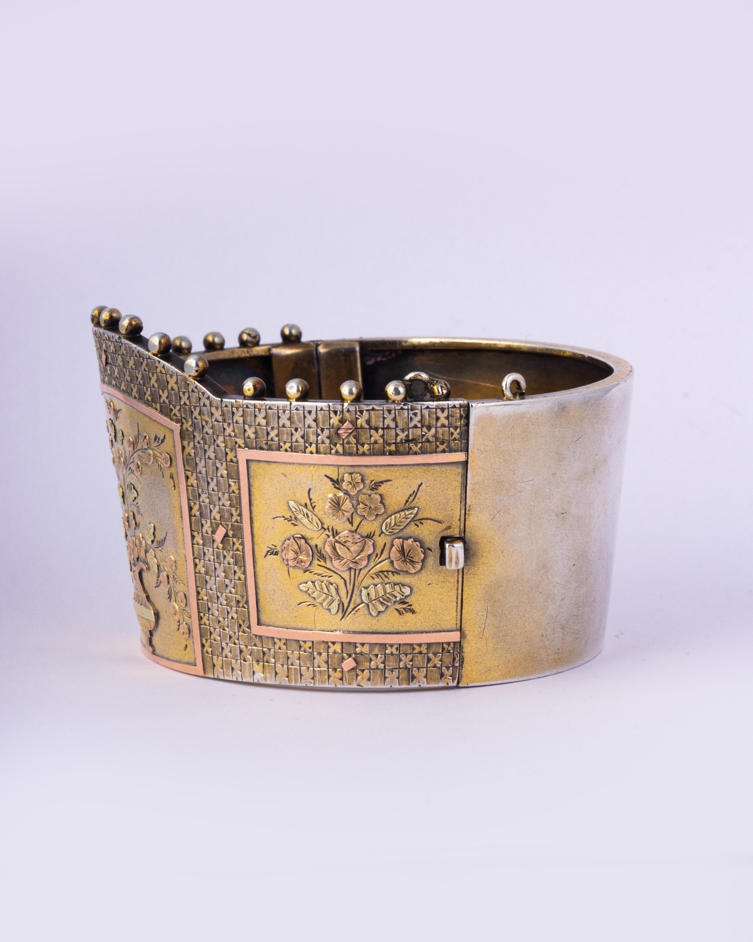 Ce large bracelet en argent brillant présente un magnifique motif représentant un vase de fleurs créé en superposition d'or jaune et rose. La gravure est si fine et si belle. 

Diamètre intérieur : 55 mm 
Largeur : 41mm 

Poids : 41,1 g