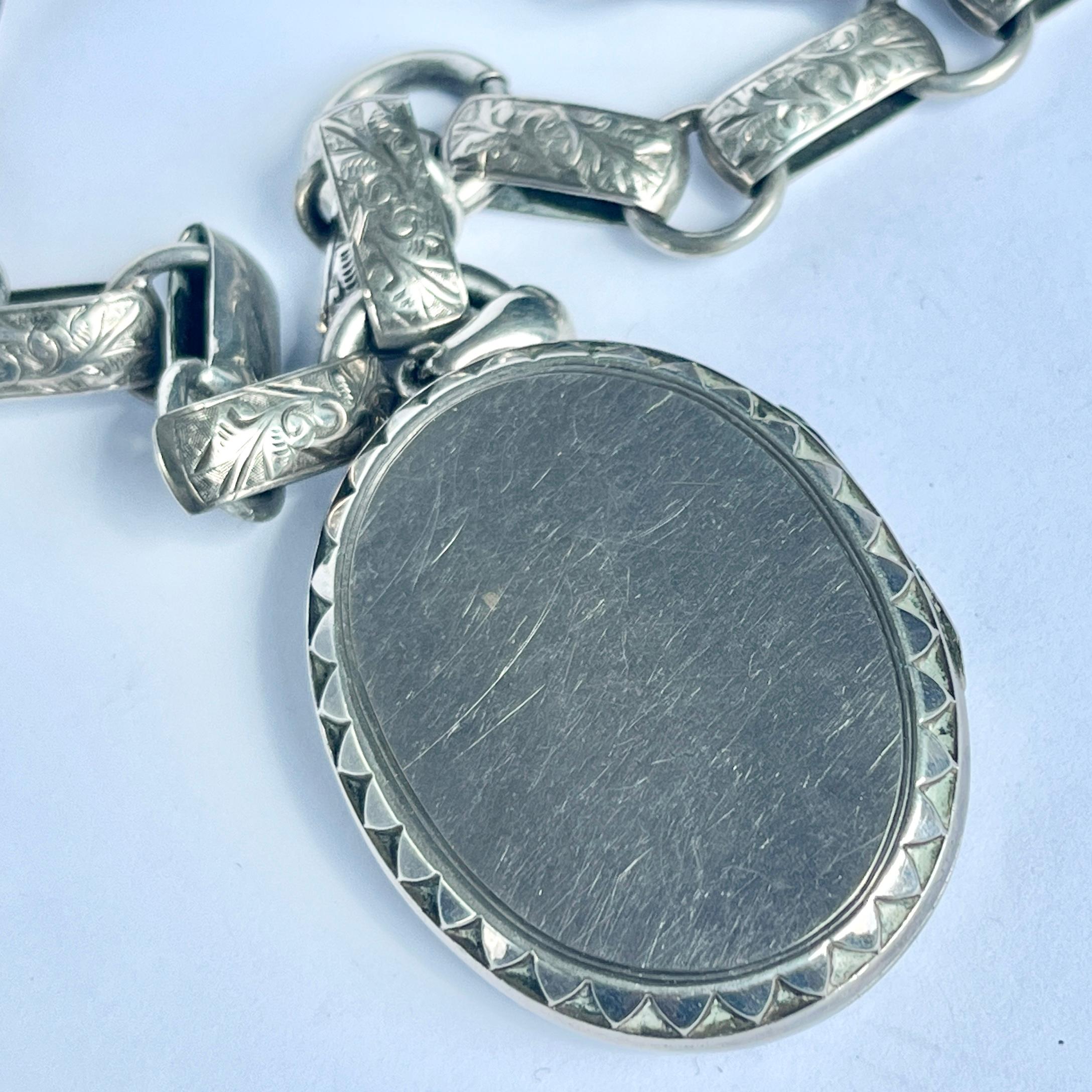 This locket has great detail on the front with engraving and raised lines of silver. The engraving features leaves and vines. The inside is left empty for your treasures. The necklace has two bolt clasps so can be made slightly shorter and you can