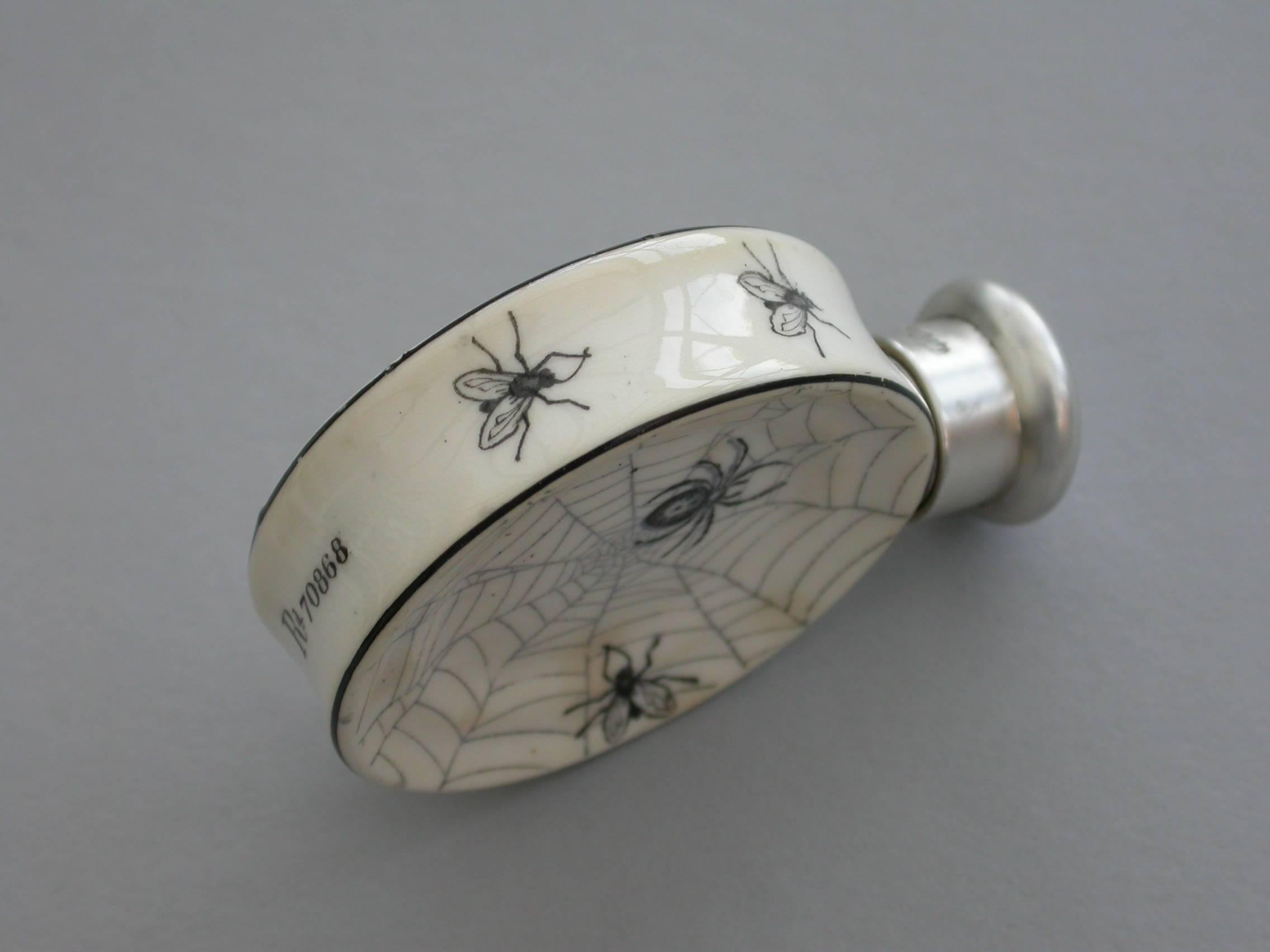 An extremely rare Victorian silver mounted porcelain scent bottle of dished circular form, decorated in monochrome enamel with spiders webs and fly's. The base with the registered design number 70868. Hallmarked silver screw-off top.

By Sampson