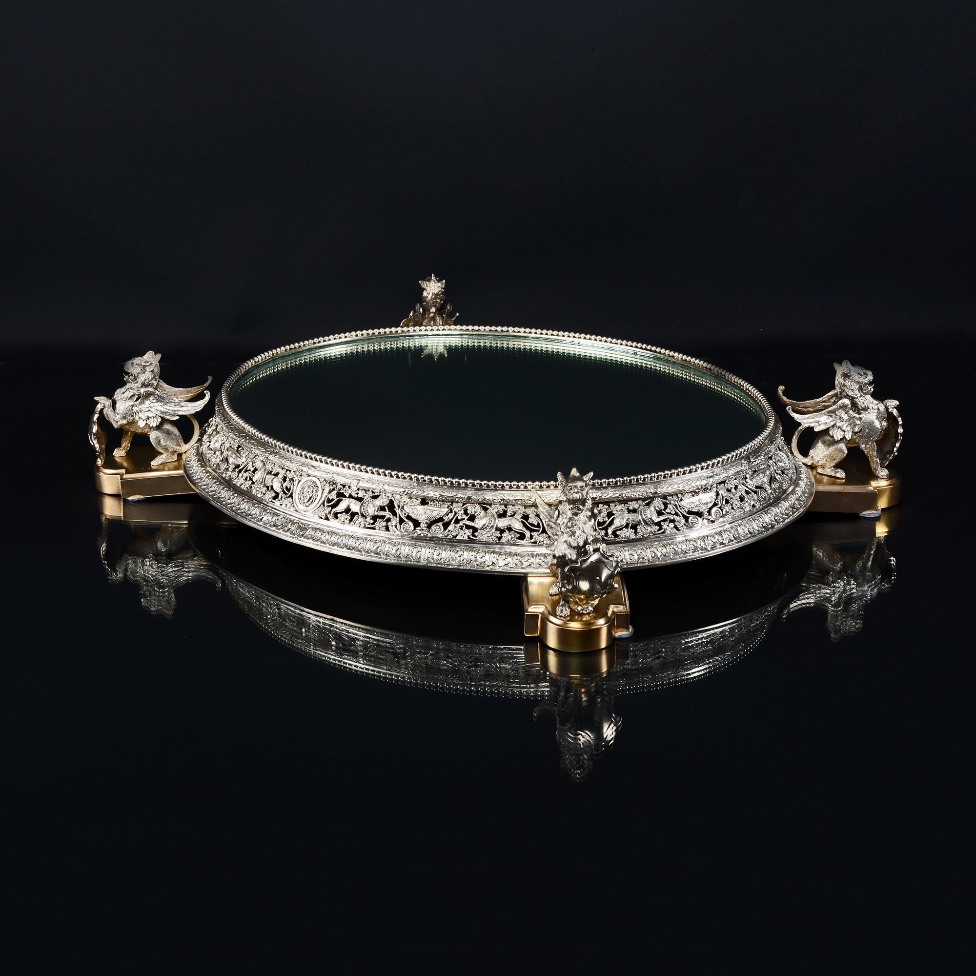 This beautiful silver plateau, oval in form, has finely cast and hand-chased classical scenes running round the border, incorporating lions entwined with grape vines and Bacchanalian masks. The central section is pierced openwork allowing the dark