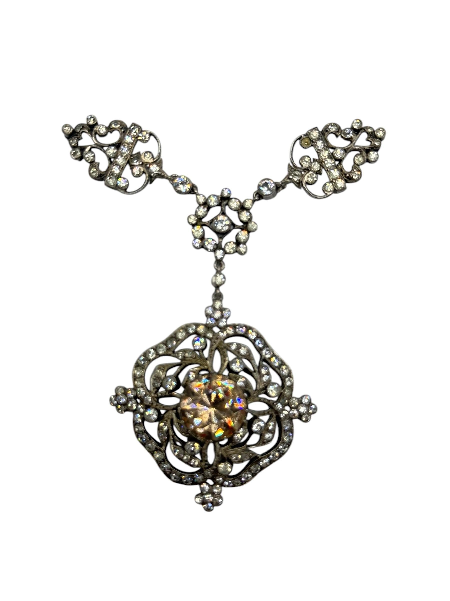 Antique Victorian silver pendant necklace featuring an openwork floral motif set with paste stones and suspended from a black ribbon choker. The central element showcases a round-cut champagne-colored paste stone, approximately 10mm in diameter, in