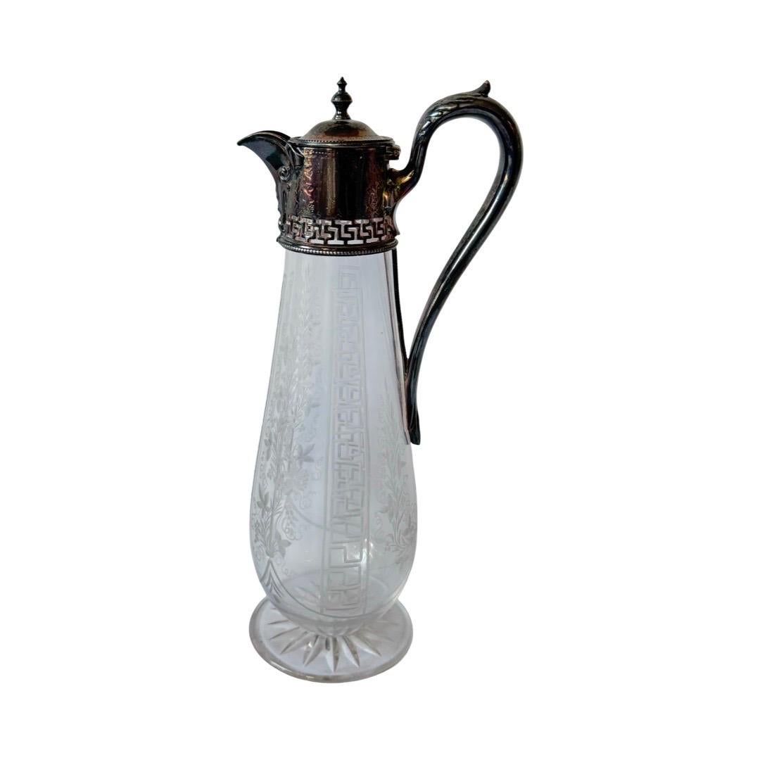 Elegante caraffa vittoriana con montatura placcata in argento con dettagli a chiave greca e motivi botanici finemente incisi. Il corpo in vetro è splendidamente inciso con motivi floreali e geometrici e poggia su una base circolare tagliata a