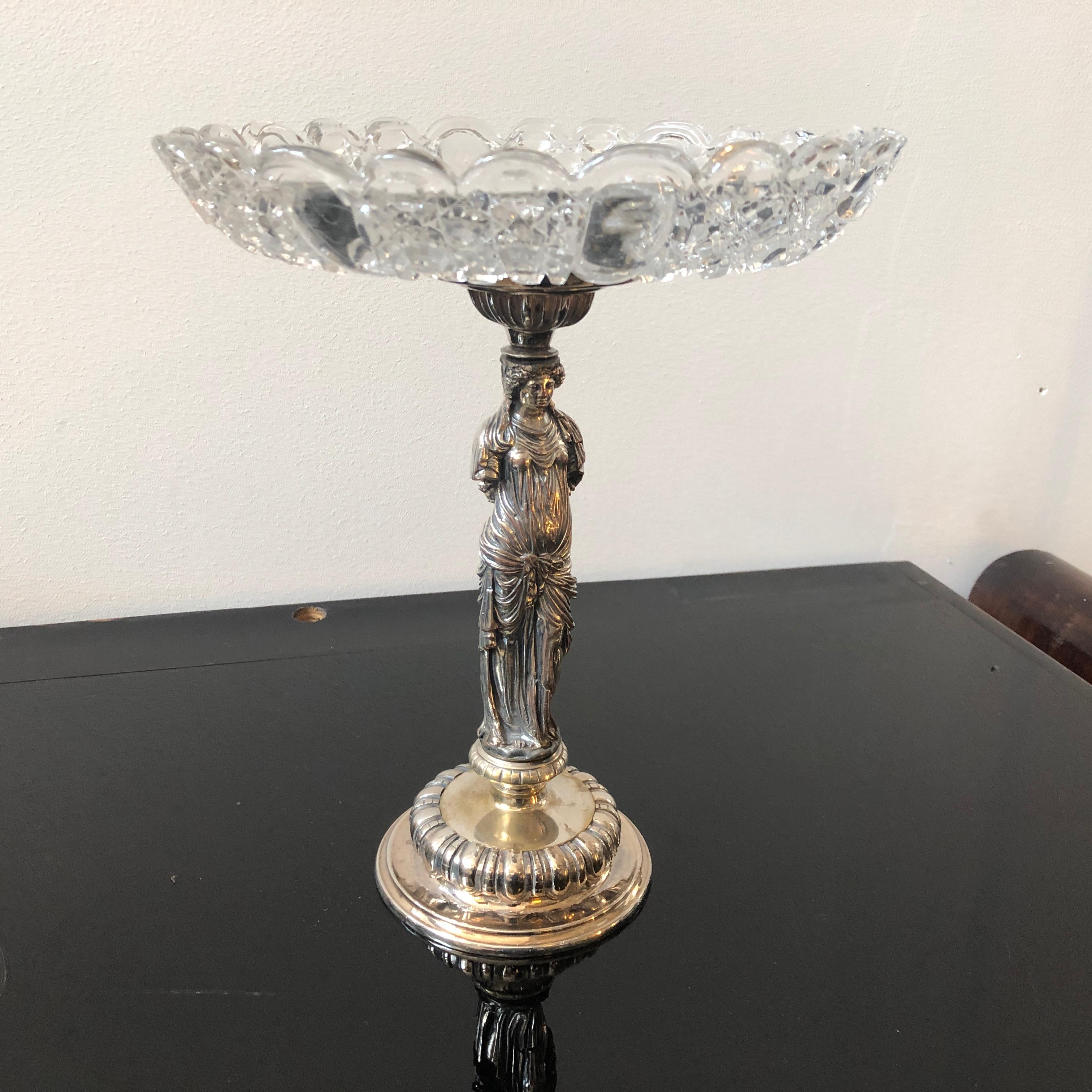 Decorative and sophisticated centerpiece in silver plate. The base is made with manual lathe in single body and then is embellished with Fine embossed fluted decoration. The central part is formed by a fusion statue representing a Greek caryatid,