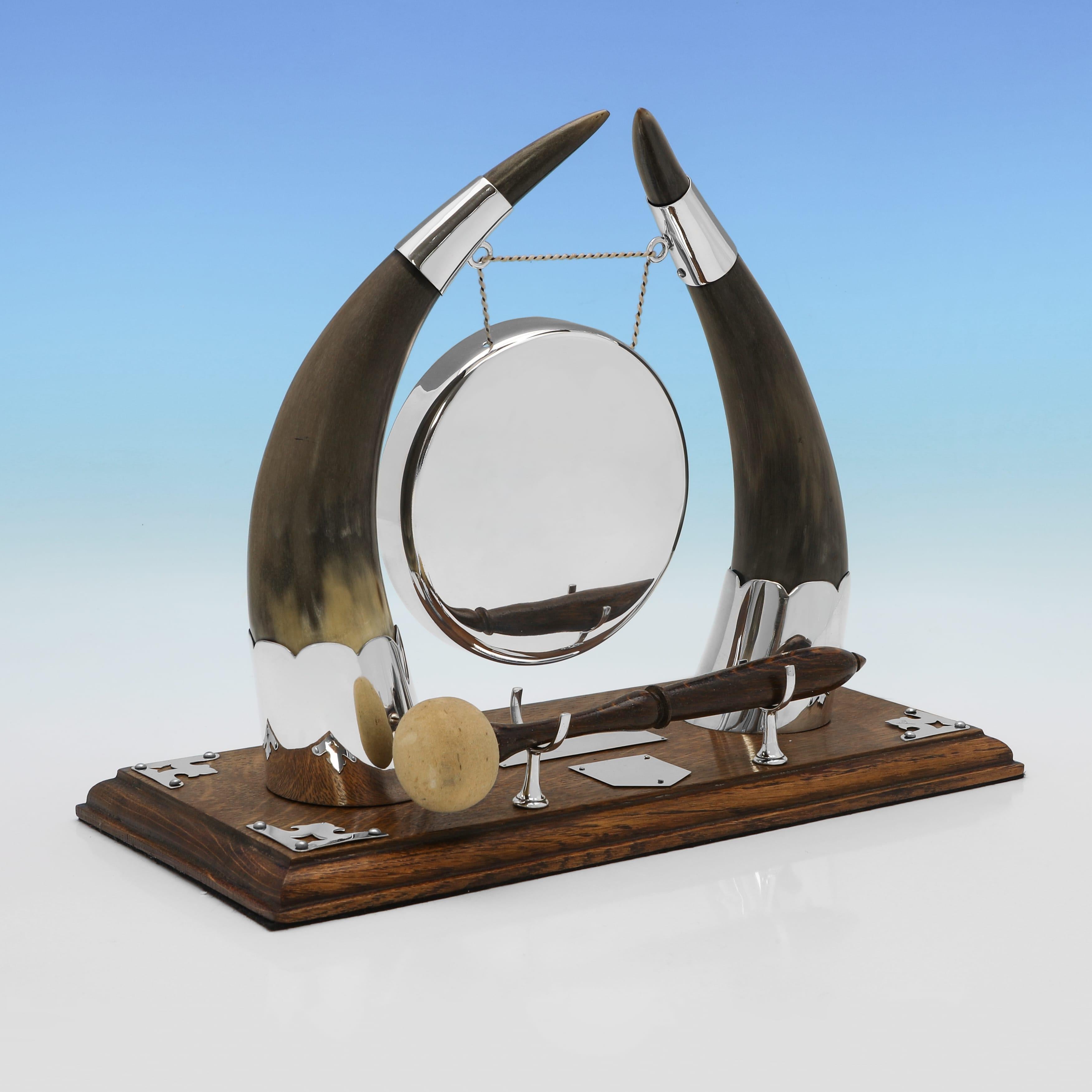 Made in England circa 1890 by Walker & Hall of Sheffield, this antique silver plated gong is mounted on a polished oak base and supported by a pair of natural cow horn uprights with silver plated mounts. The circular gong hangs from a chain between