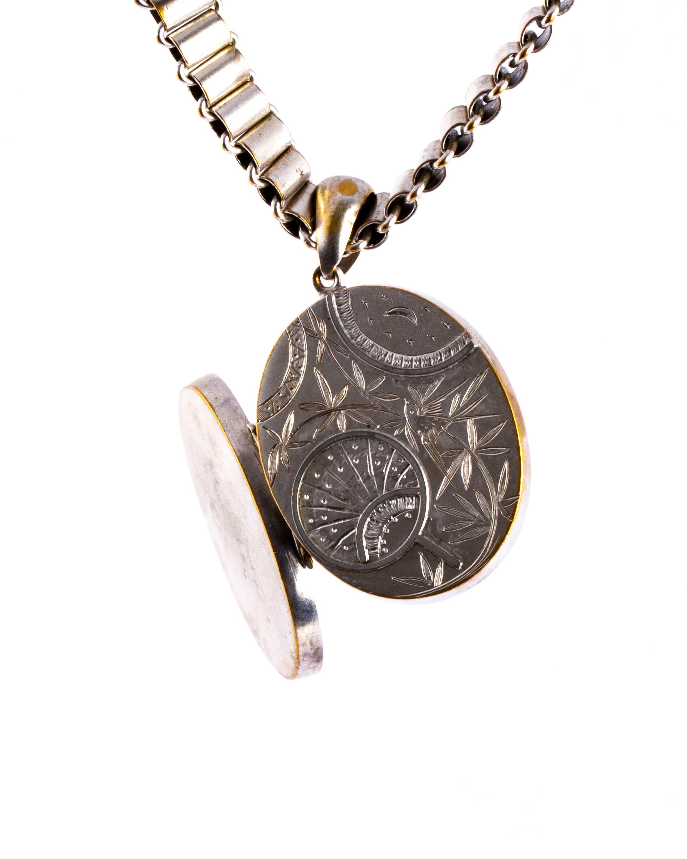 This wonderful locket has engraving of a sunrise with a bird and leaf motif surrounding it. The back of the locket is plain glossy silver. The collar is simple and made up of smooth rolls of silver.  

Locket Dimensions: 43mm x 35mm
Chain length: