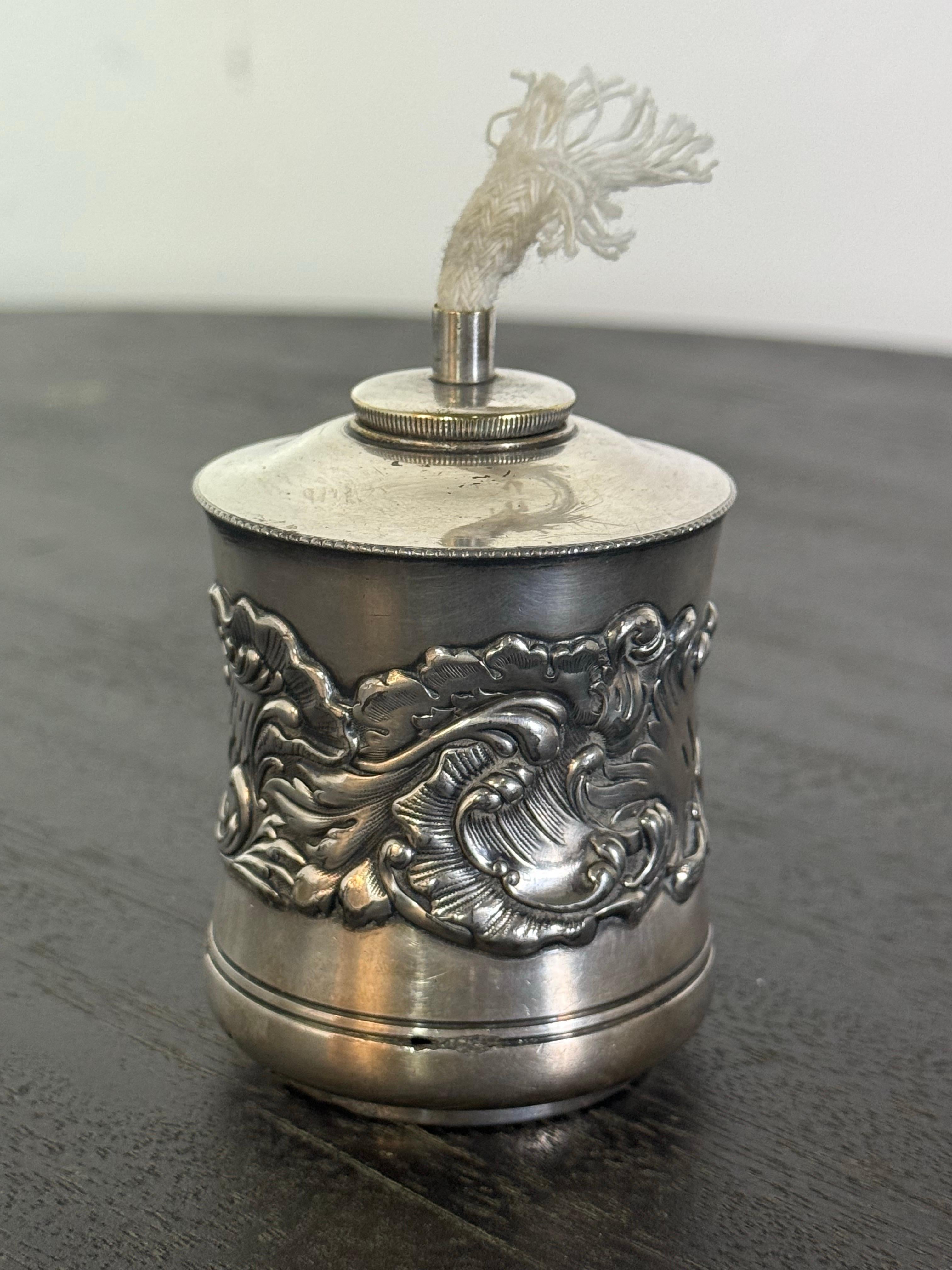 Il s'agit d'une lampe à huile ou d'un briquet de table victorien plaqué argent, fabriqué par la Derby Silver Company, comme l'indique le poinçon sur le dessous. La pièce date probablement de la fin du XIXe siècle ou du début du XXe siècle (vers