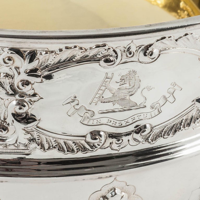 A large, heavy and impressive silver rose bowl in the Rococo style of Paul de Lamerie, hand-chased with a cartouche on either side. One cartouche is plain while the other has a family rest of a lion holding a ladder with the Latin motto 'in promptu'