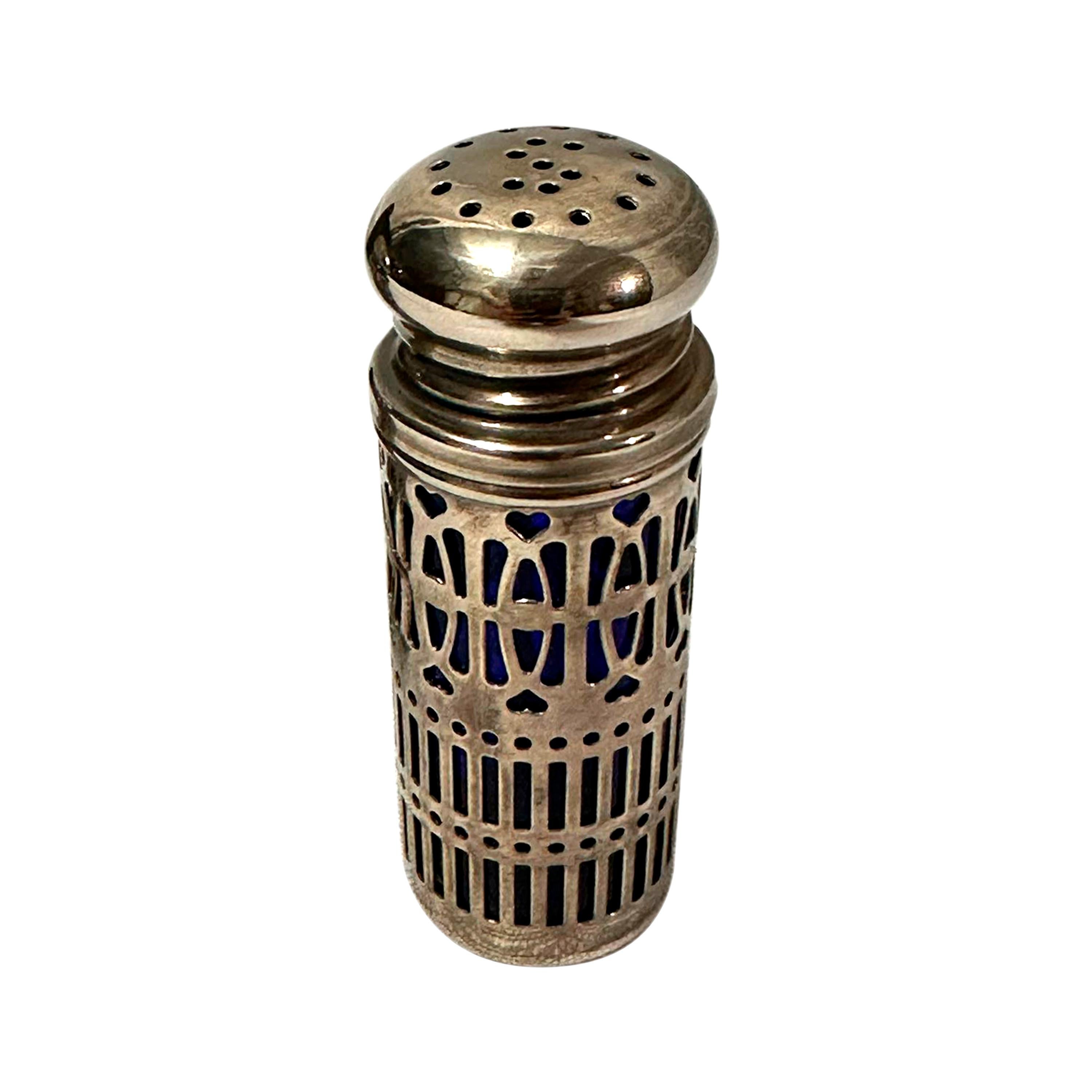 Juego de salero y pimentero de plata cincelada a mano e interior de cristal azul, está estampado con contrastes ingleses pertenecientes a la época victoriana. Inglaterra, siglo XIX, hacia 1860.