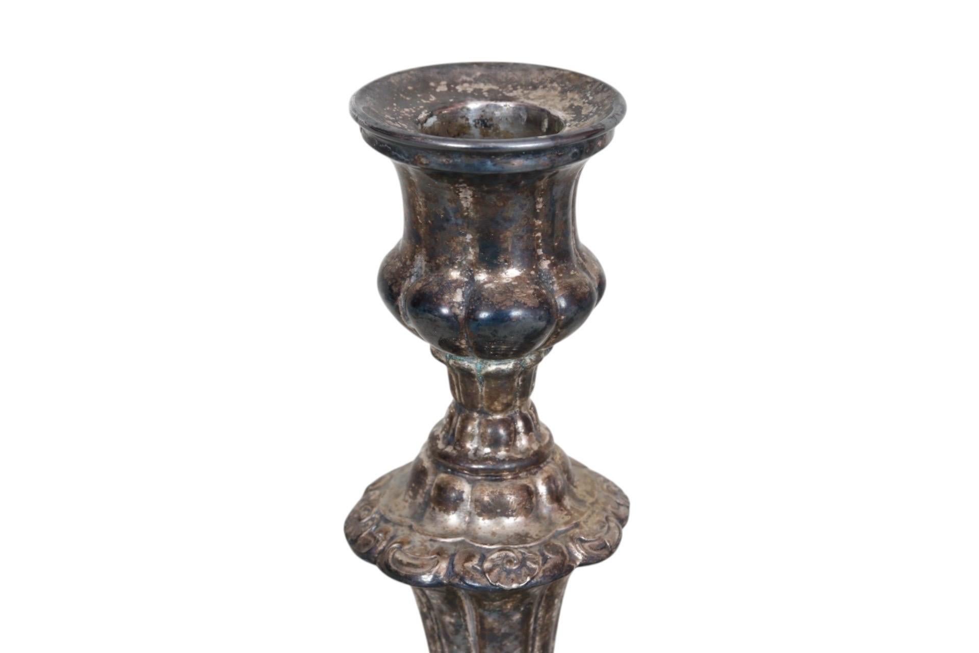 A pair of Victorian silverplate candlestick holders circa 1890. Fluted columns and gadrooned knops are decorated with shell and swag details. Dimensions per candlestick holder.