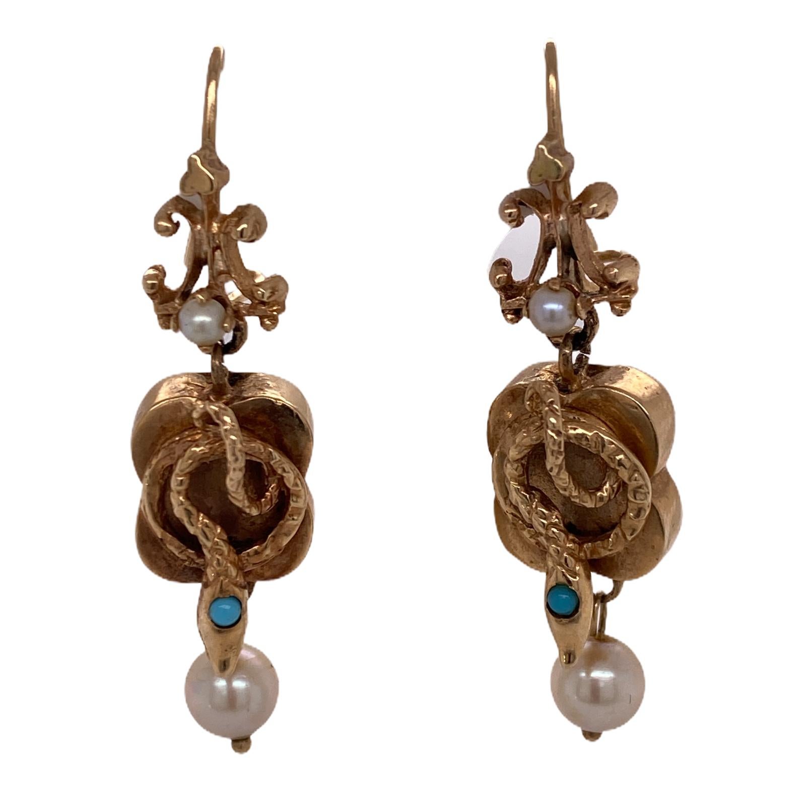 Fabulous Victorian snake drop earrings fashioned in 14 karat yellow gold. The earrings feature snake designs accented with turquoise gemstone and pearl drops. The light weight earrings measure 1.5 inches in length, .5 inches in width, and have hook