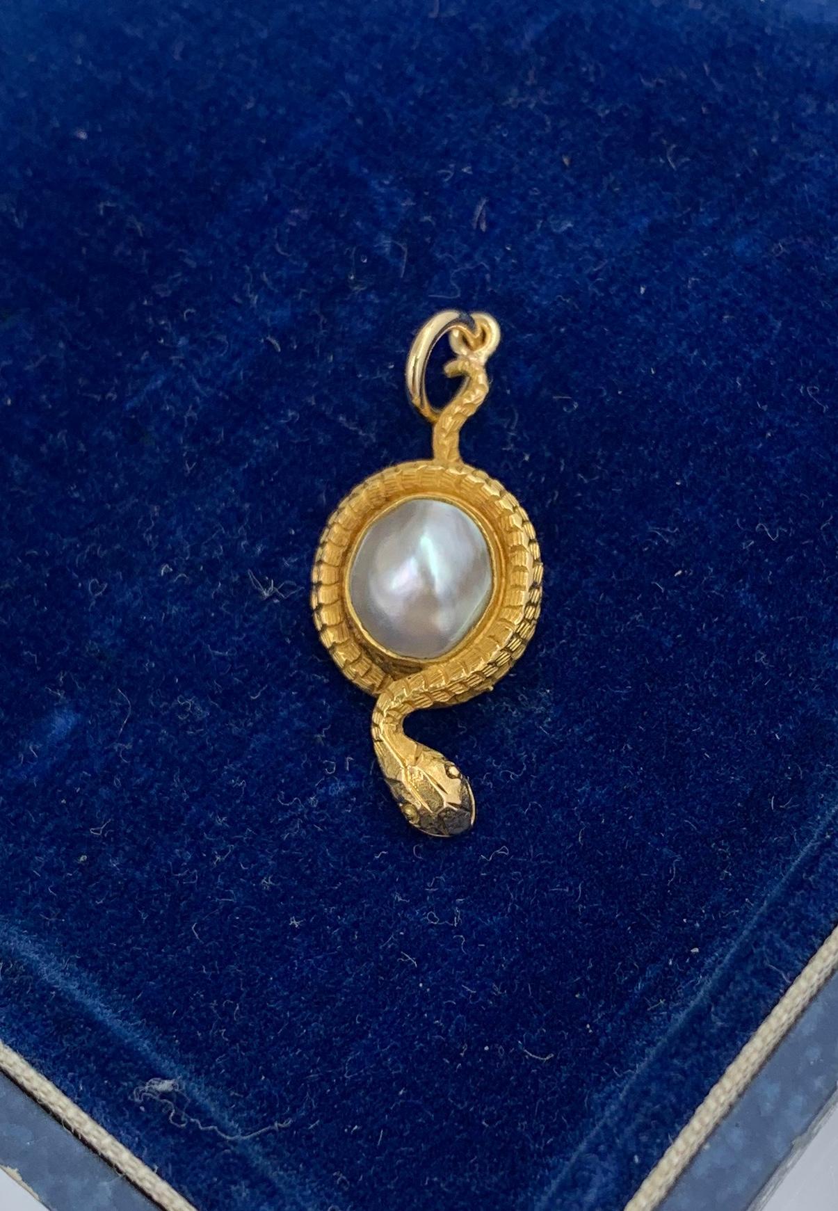 This is a rare antique Victorian Snake Pendant Necklace depicting a snake or serpent wrapped around an egg or globe.  The snake is beautifully created in 14 Karat yellow gold.  The egg or globe is a gorgeous Baroque Pearl of a stunning silver color.
