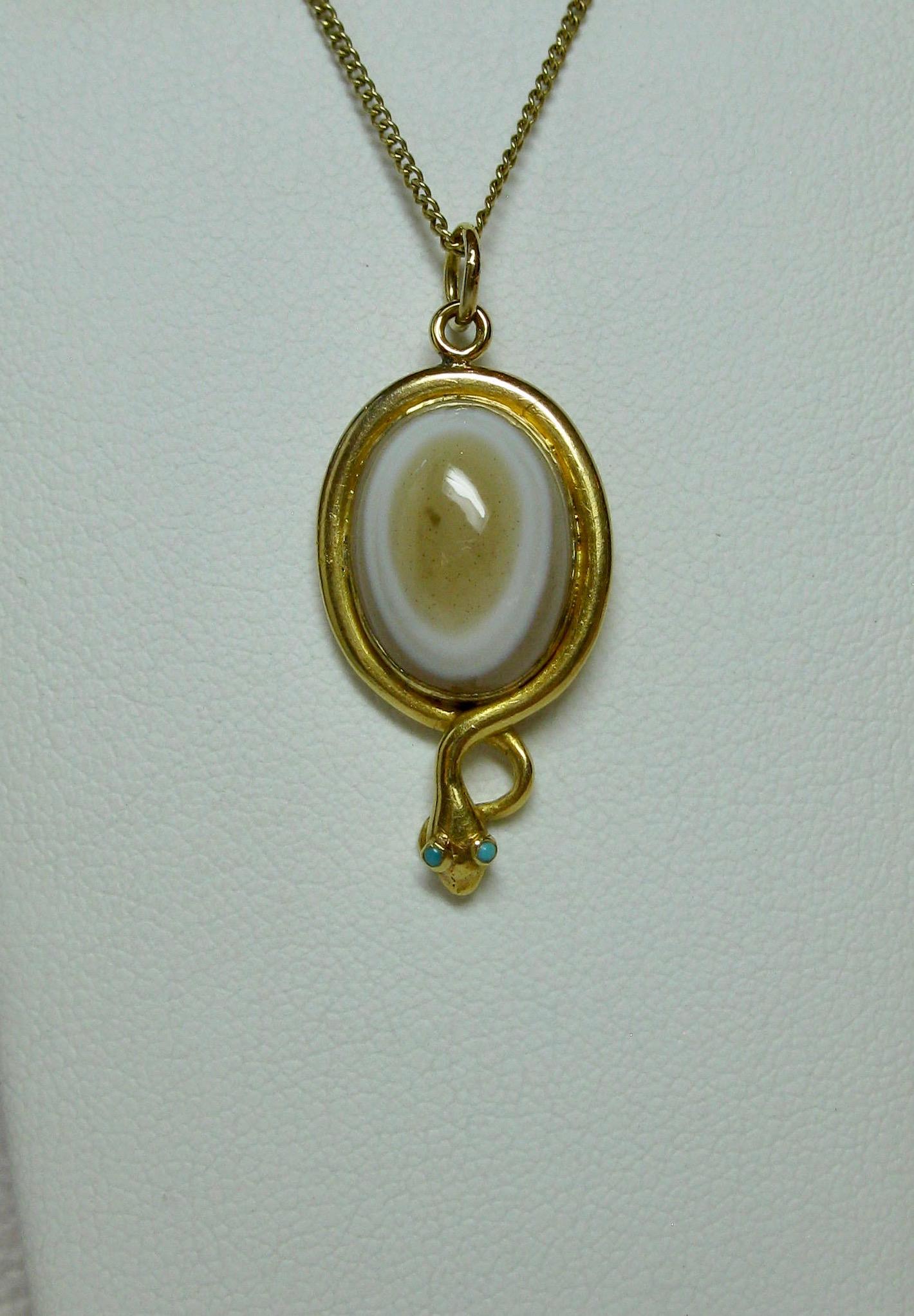 A rare antique Victorian Snake Pendant depicting a snake or serpent wrapped around an egg.  The snake beautifully created in 18 Karat gold.  The egg a gorgeous Banded Agate.  The snake's eyes two Persian Turquoise cabochons. The snake pendant dates