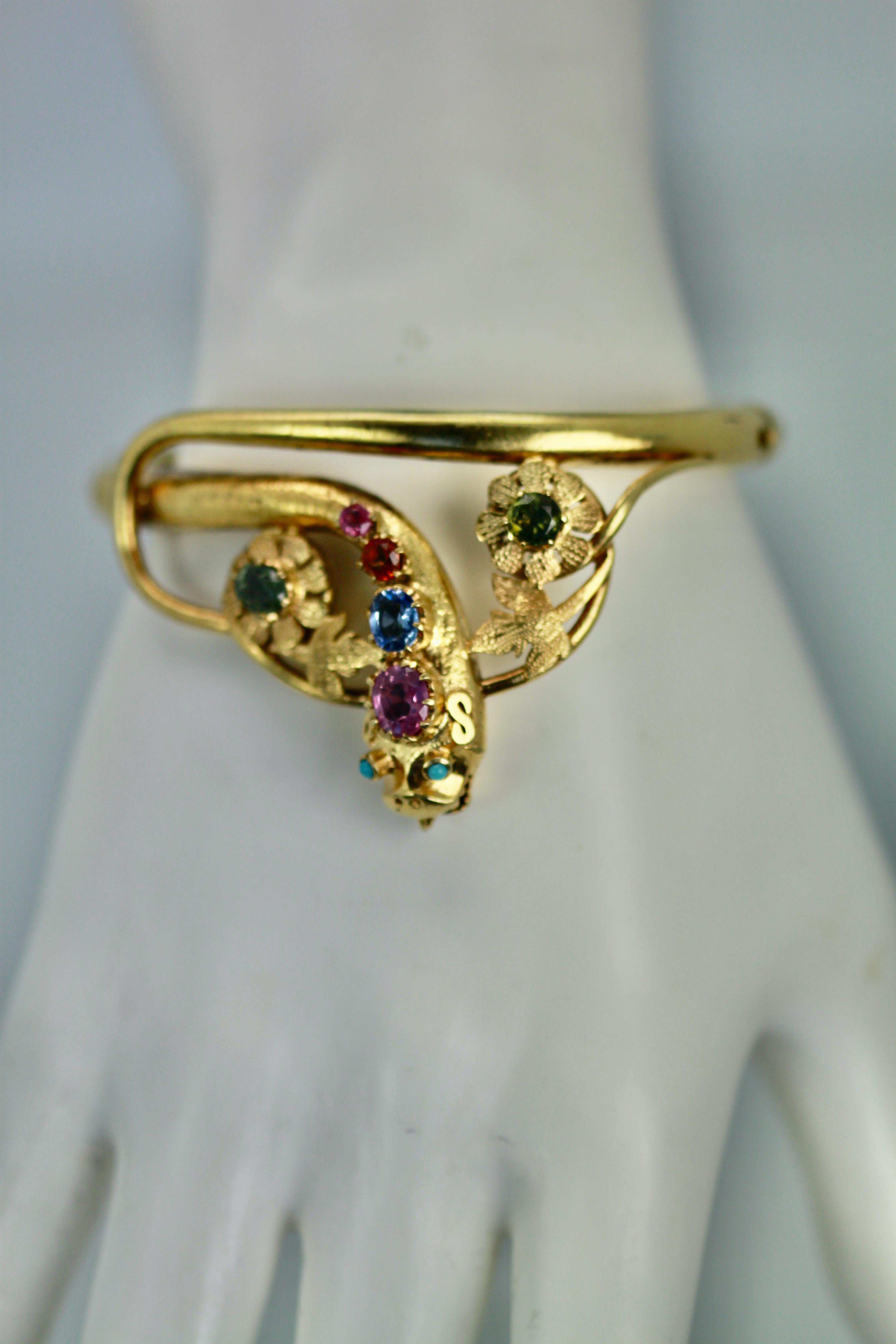 This unusual snake bracelet is set with multi-colored Sapphires and is quite special.  This bracelet is done in 14K yellow gold and set with a cushion cut Blue Sapphire, Pink, Orange Sapphires to the head and body.  Cabochon Turquoise eyes and Green