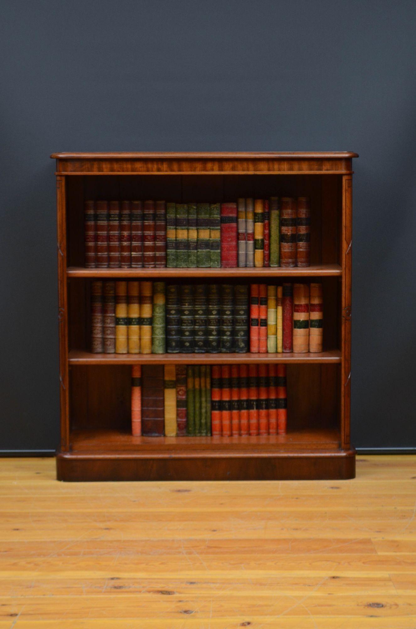 Sn5605 English Victorian mahogany open bookcase, having figured mahogany top with moulded edge above two height adjustable shelves flanked by rounded uprights with carved decoration, all standing on moulded plinth base. This antique bookcase is in