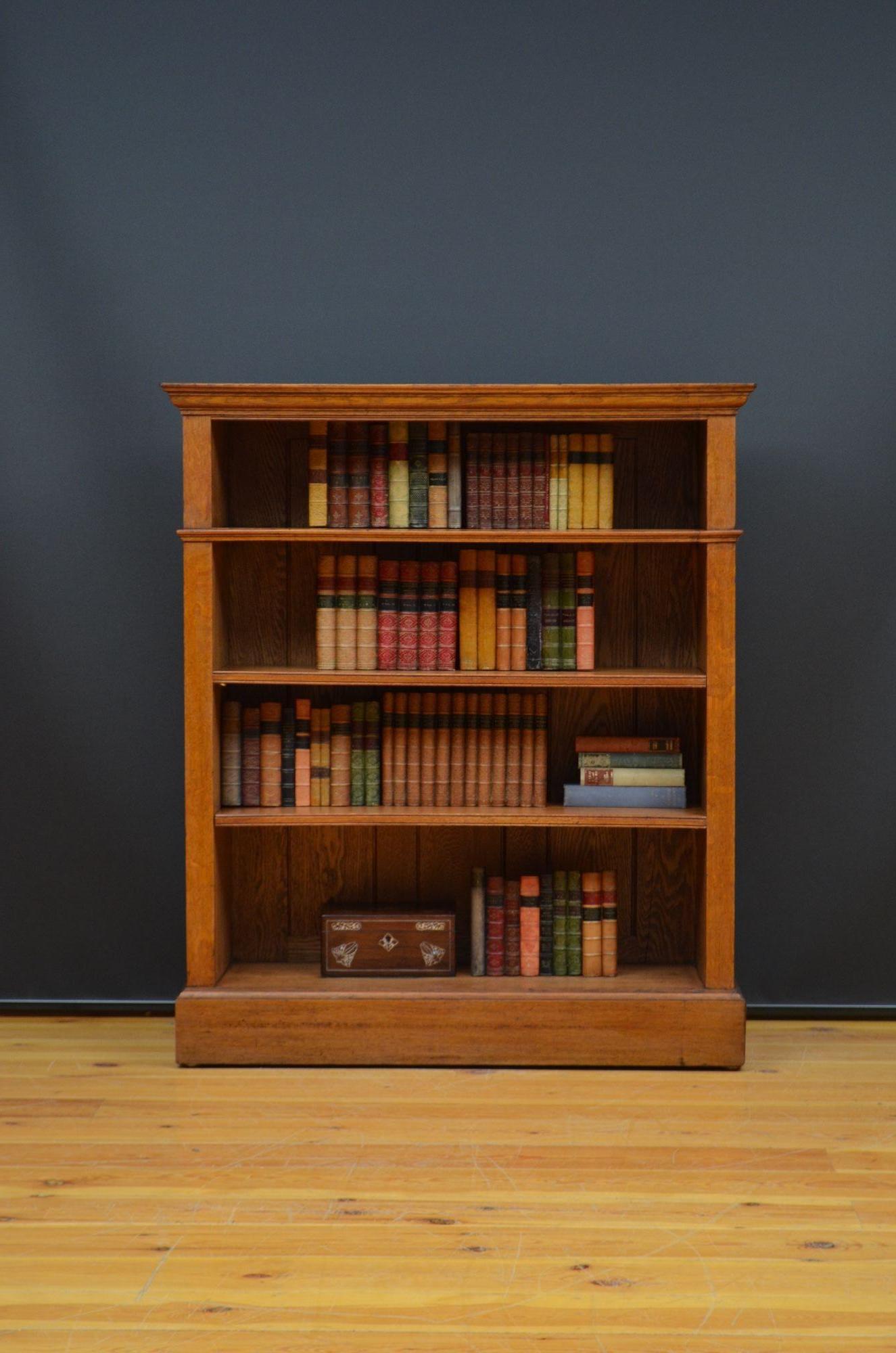 K0625 English antique solid oak open bookcase, having oversailing top with an attractive grain and moulded top above one fixed and two height adjustable shelves with reeded edges, all standing on deep plinth base with moulded edge. This antique