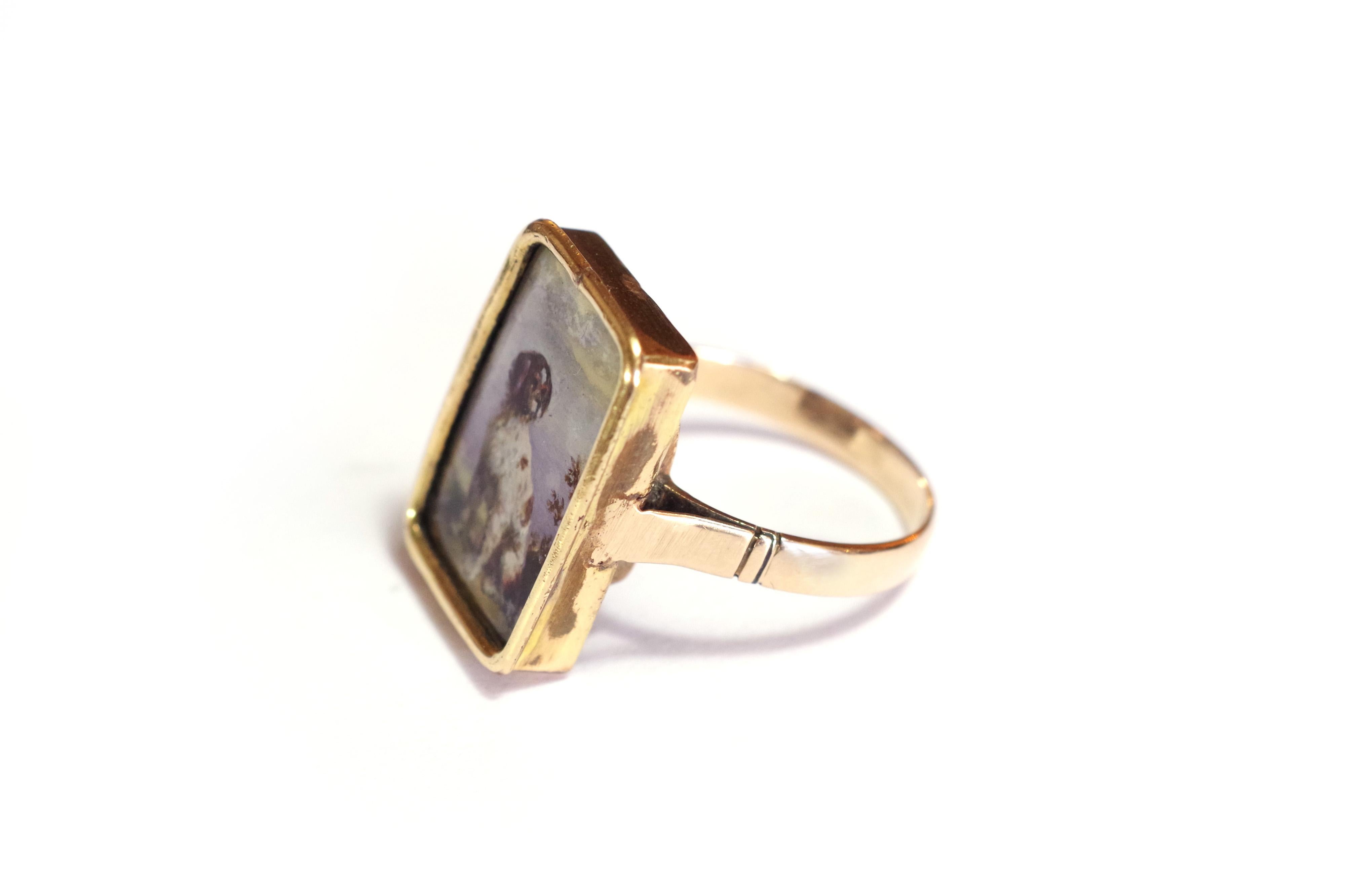 Victorian Spaniel brittany dog ring in rose gold 9 karats. Antique ring with a painted miniature, showing a sitted dog, looking to the right. It is most probably a hunting dog, Spaniel Brittany type. The miniature is painted on a white background.