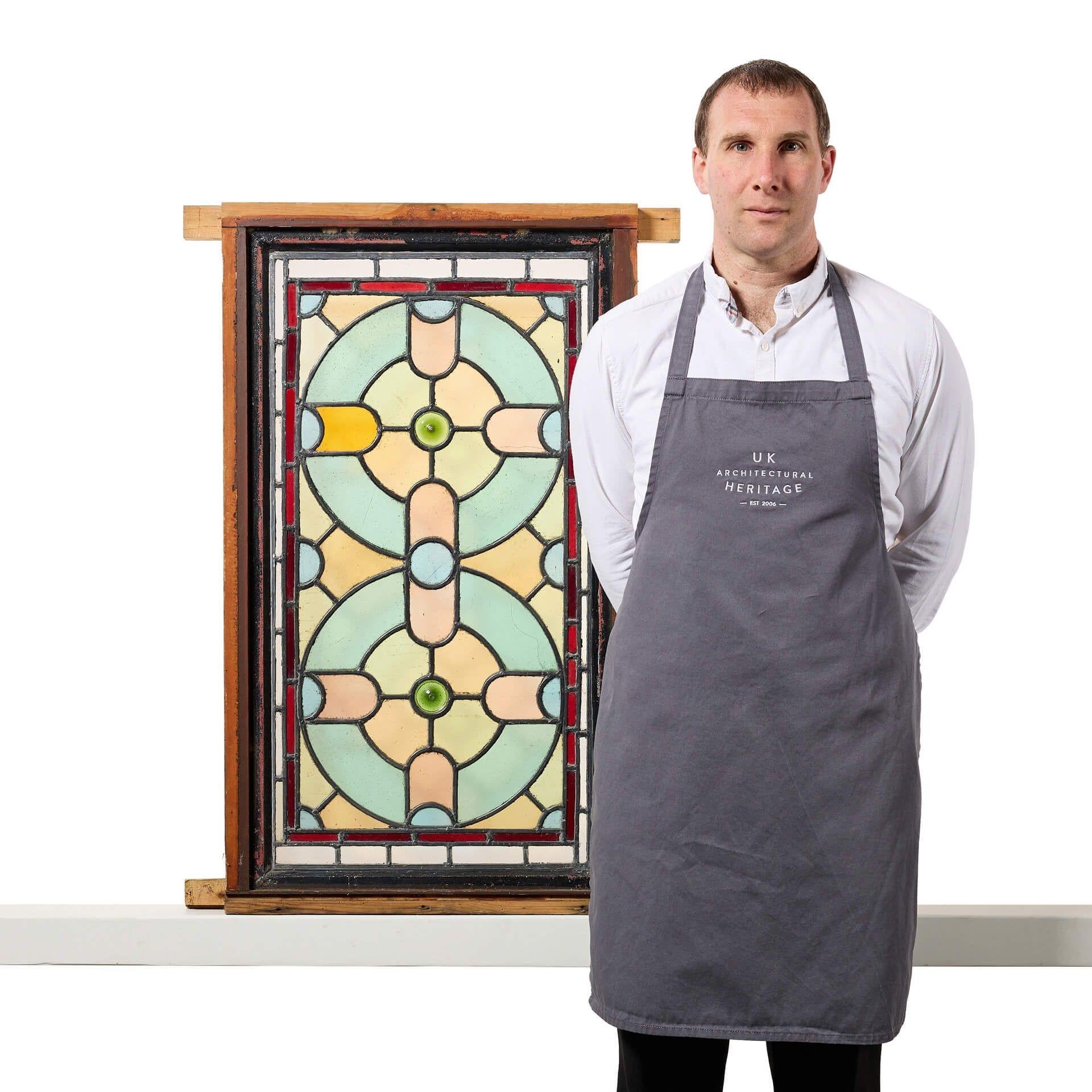 A late Victorian stained glass window panel originating from England, circa 1900. We are also selling a second window in the same design.

This colourful stained glass window is tall in scale and currently fixed into a wooden frame. The panel is