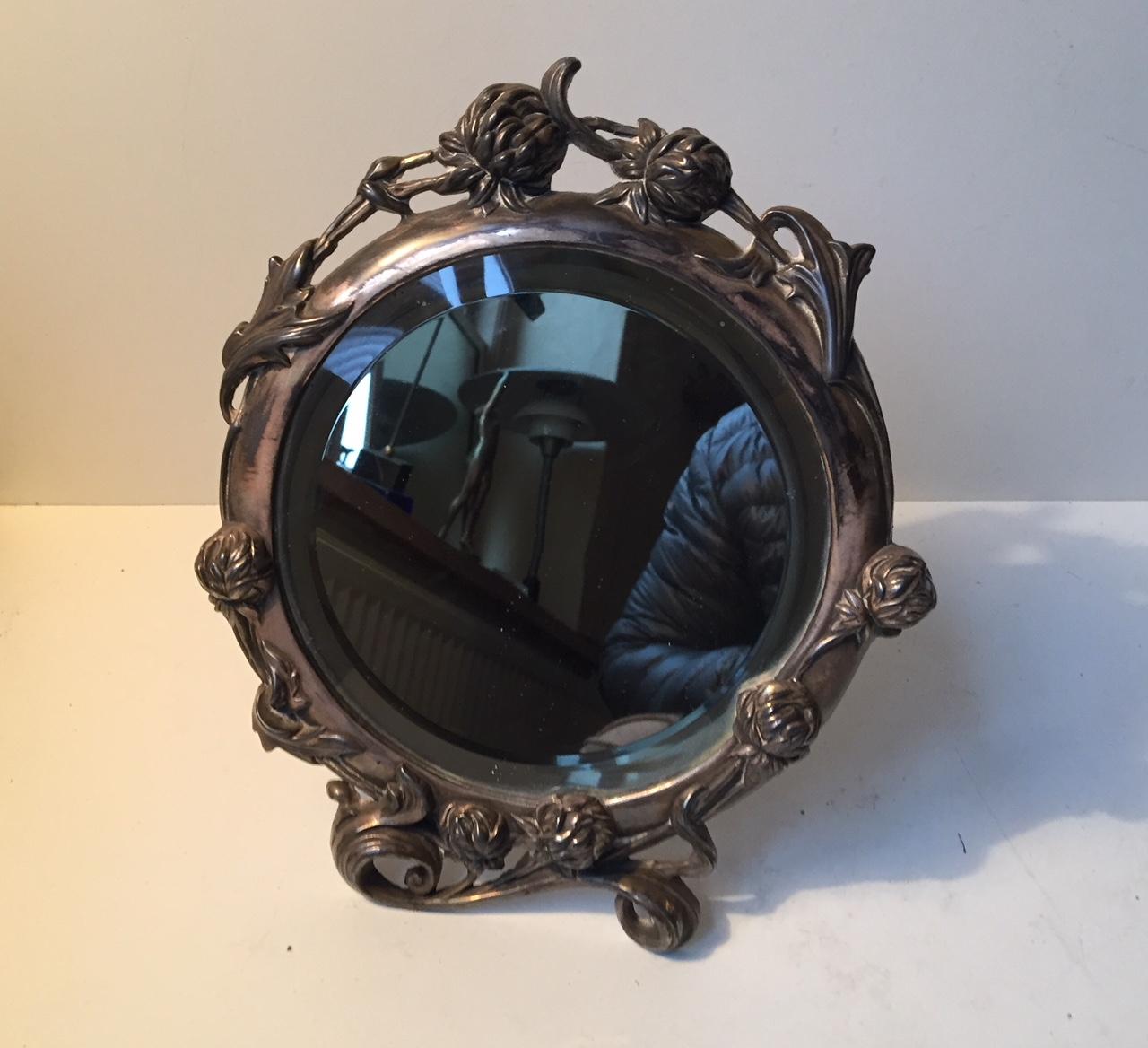 Victorian table or wall mounted vanity mirror composed of richly detailed pewter. It was manufactured in either France or England during the mid-late 19th century. The floral details are rather elongated and the style of this piece flirts with Art